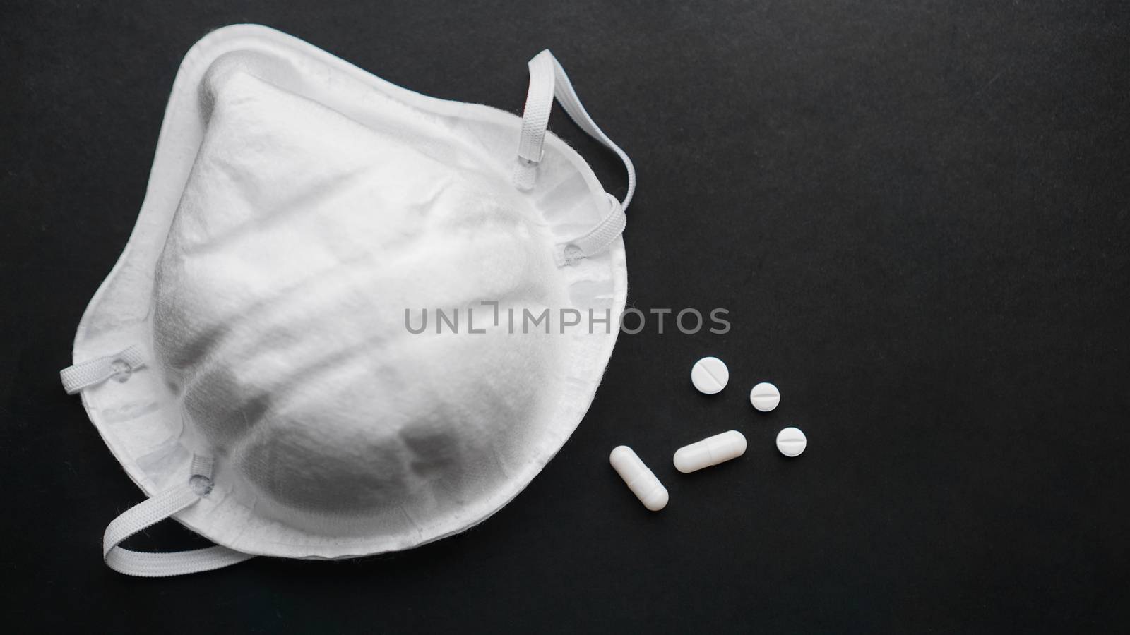 Epidemic and virus concept - white pills and masks on black background