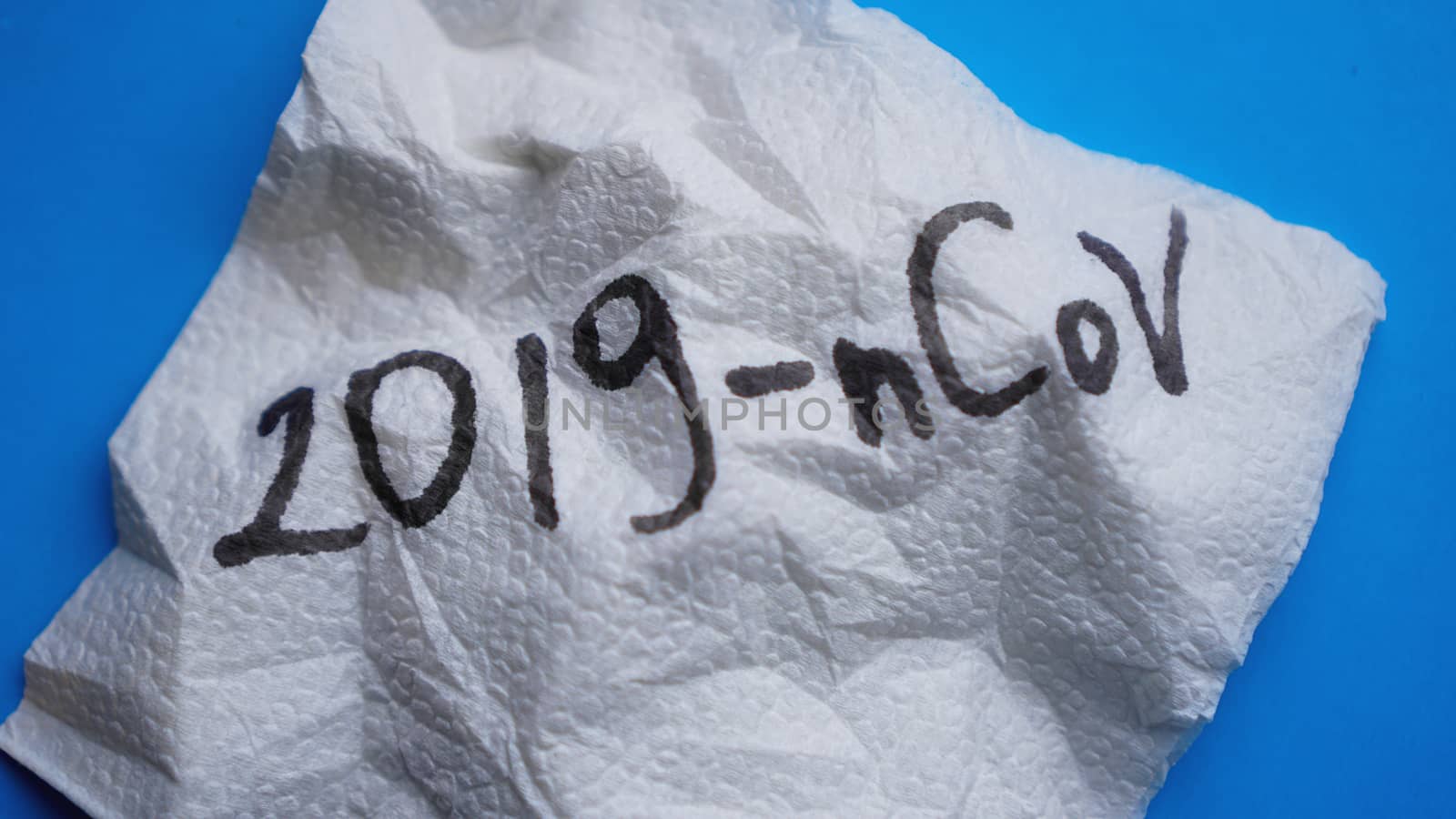 Crumpled napkin with 2019-nCoV virus on blue background. Victory over coronavirus