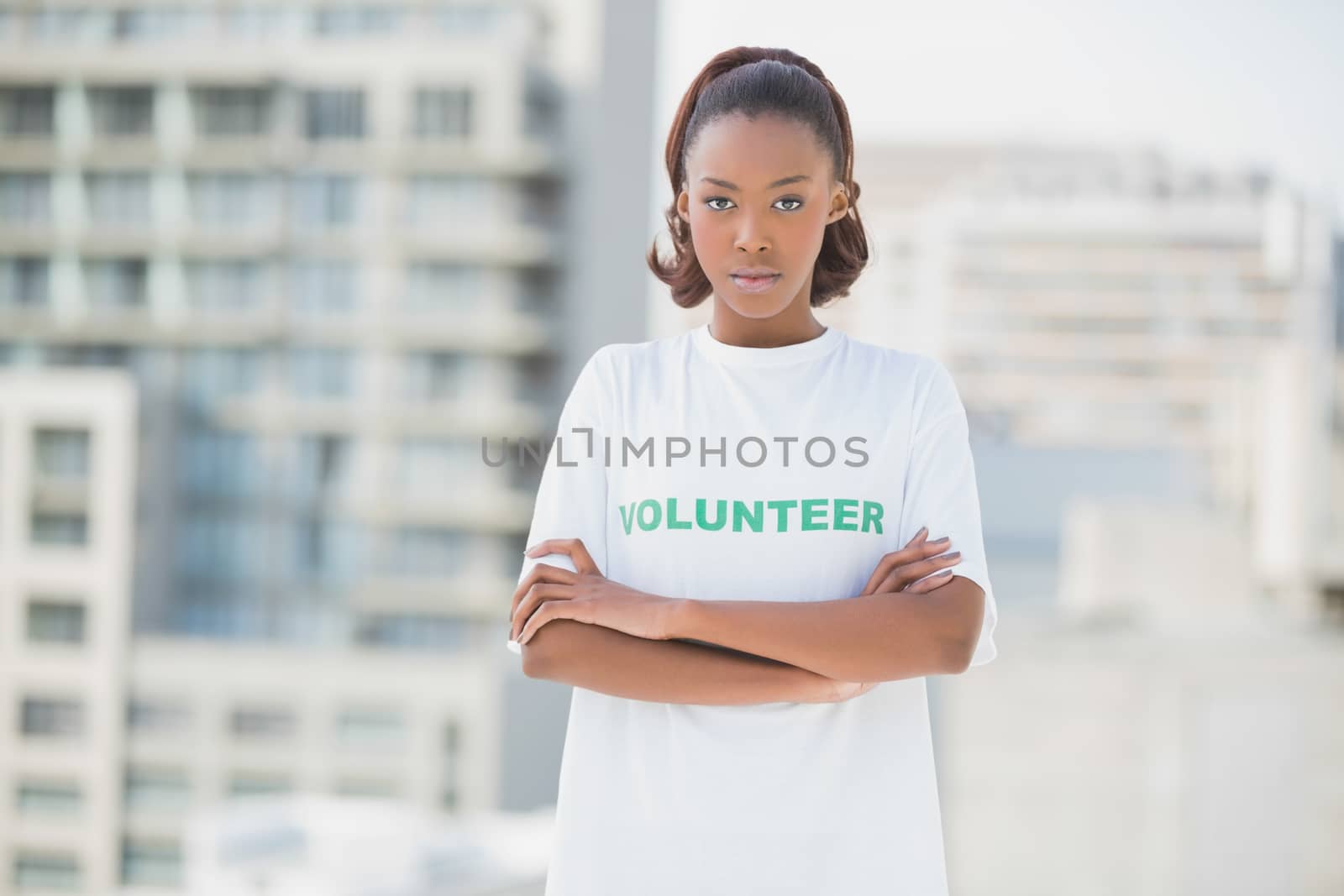 Serious woman with crossed arms outdoors on urban background