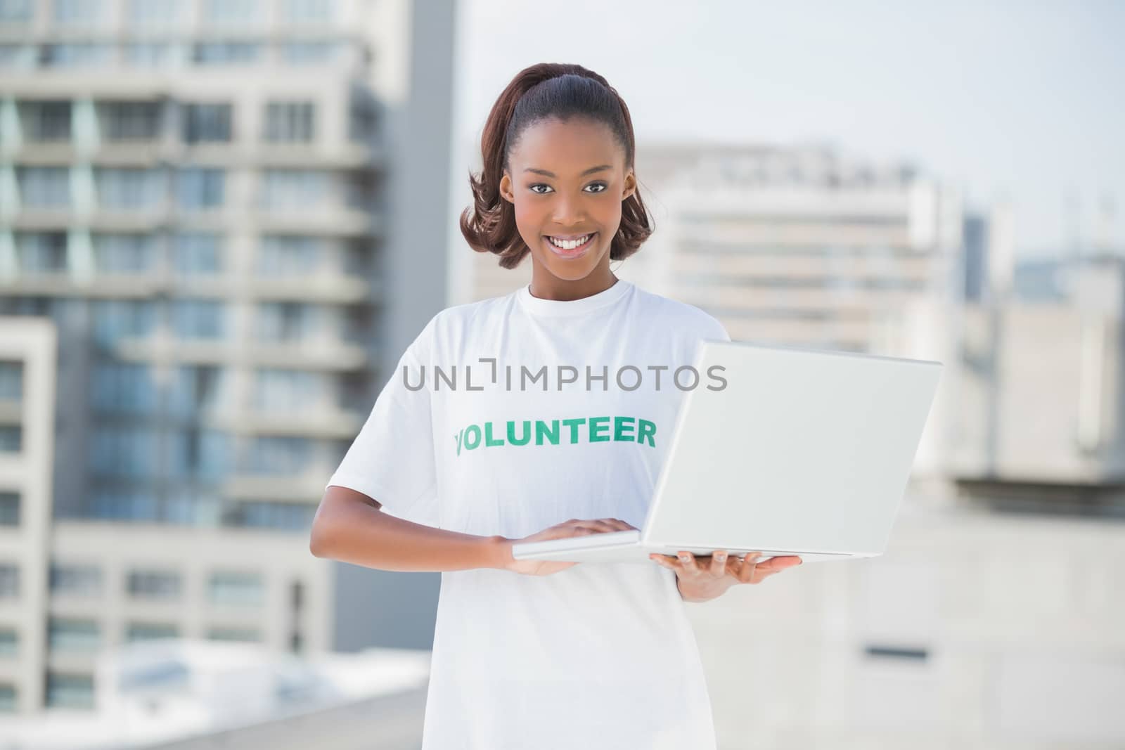 Cheerful volunteer smiling at camera outdoors on urban background