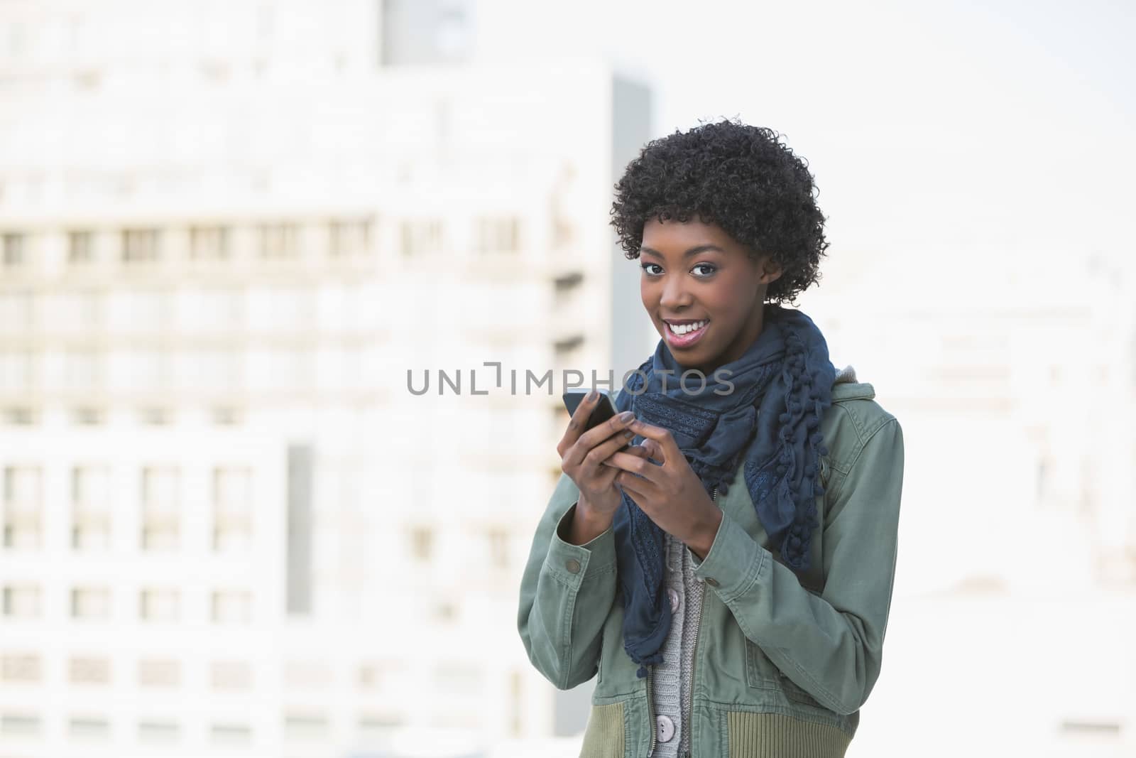 Cheerful afro model texting outdoors on a sunny day