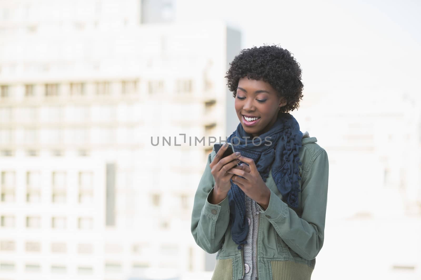 Cheerful casual model texting outdoors on a sunny day