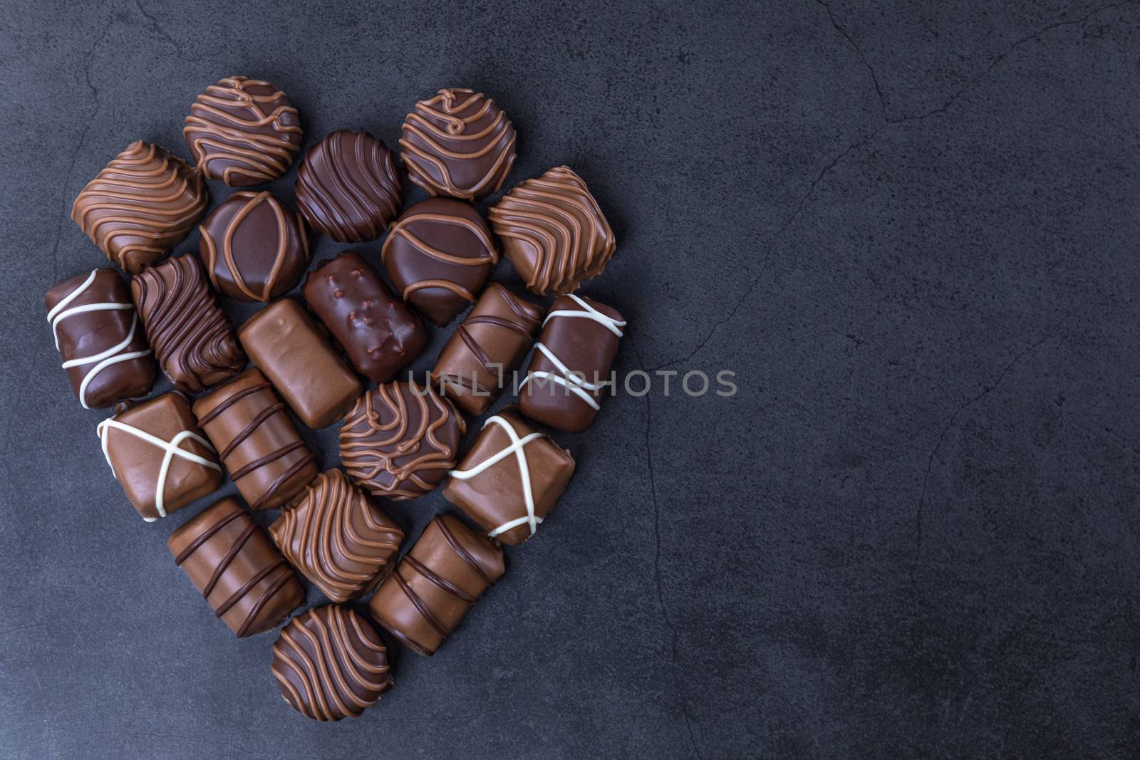 Stack of Chocolate candy in the shape of heart on a black background.  Focus on chocolate.