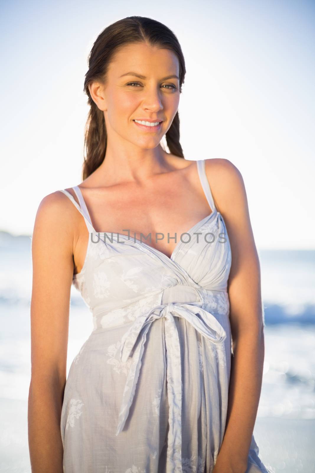 Happy model in summer dress posing on the beach at dusk