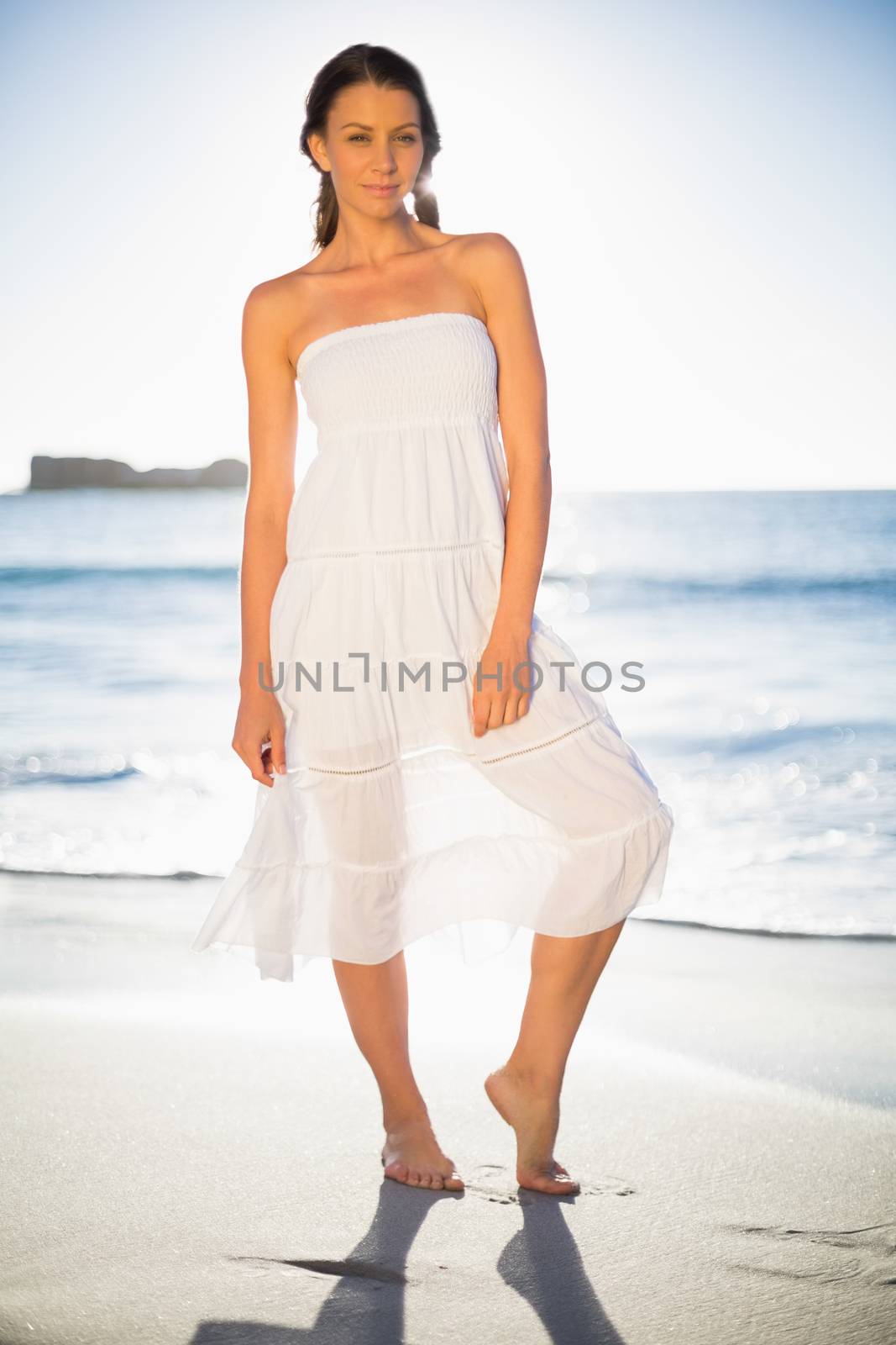 Cheerful woman in white summer dress posing on the beach at dusk