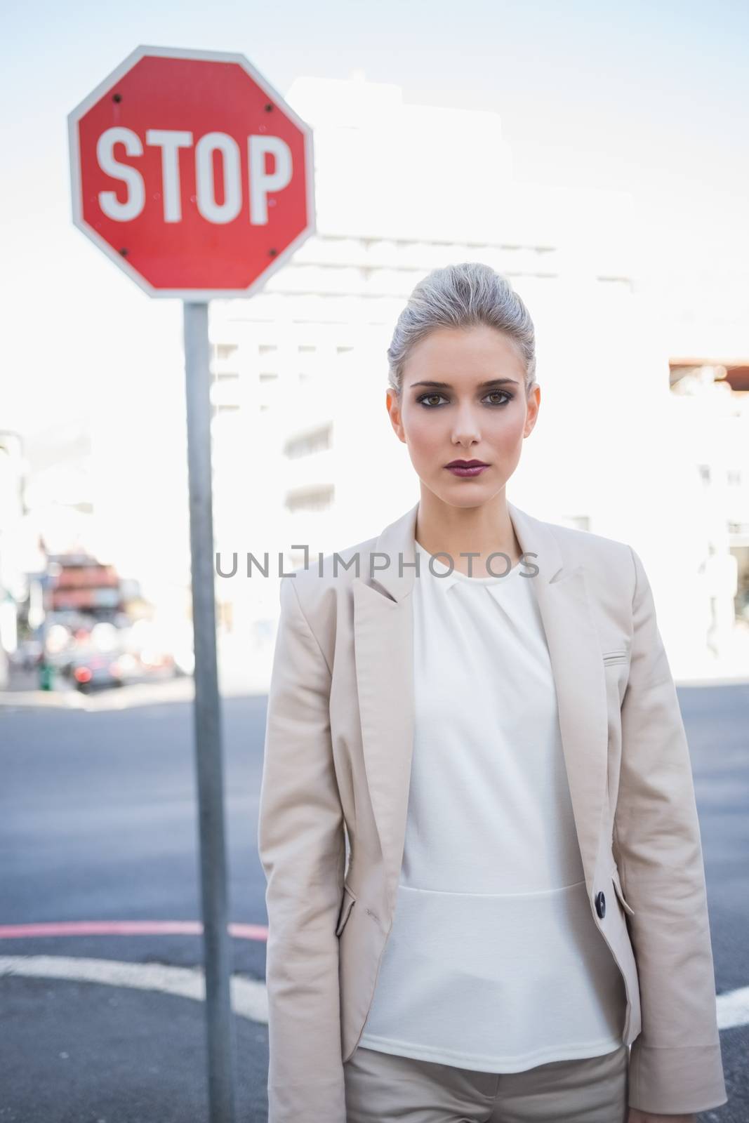 Stern elegant businesswoman posing outdoors on urban background