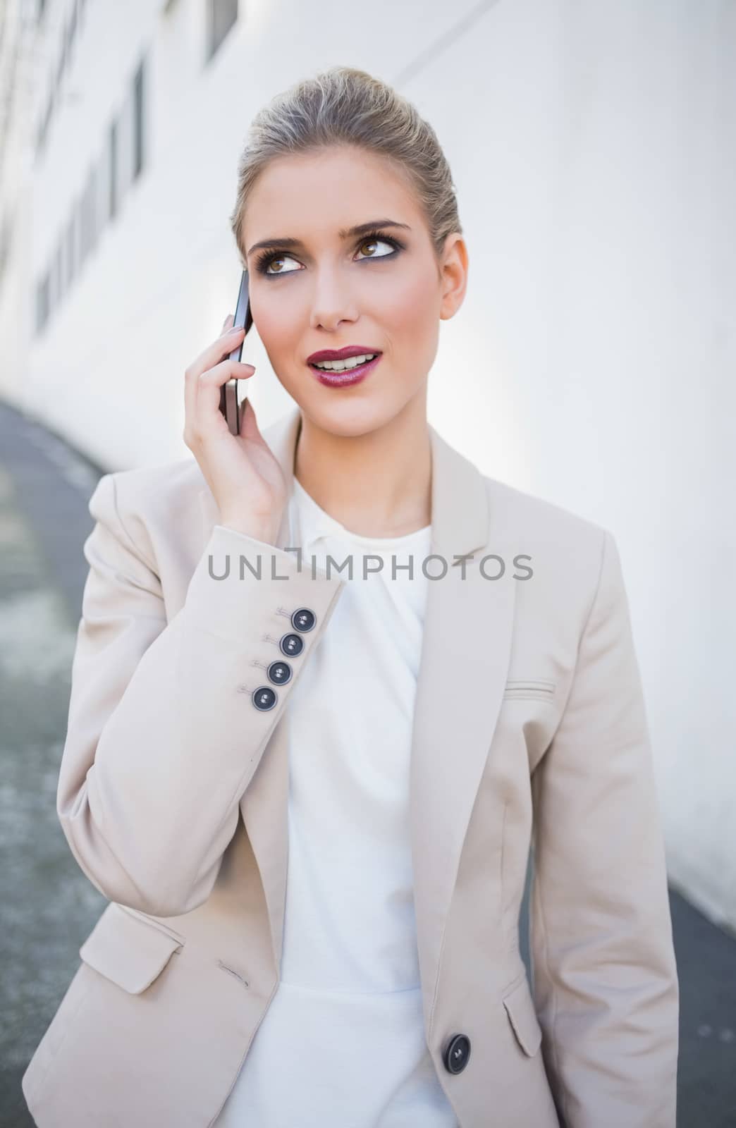 Smiling attractive businesswoman on the phone outdoors on urban background