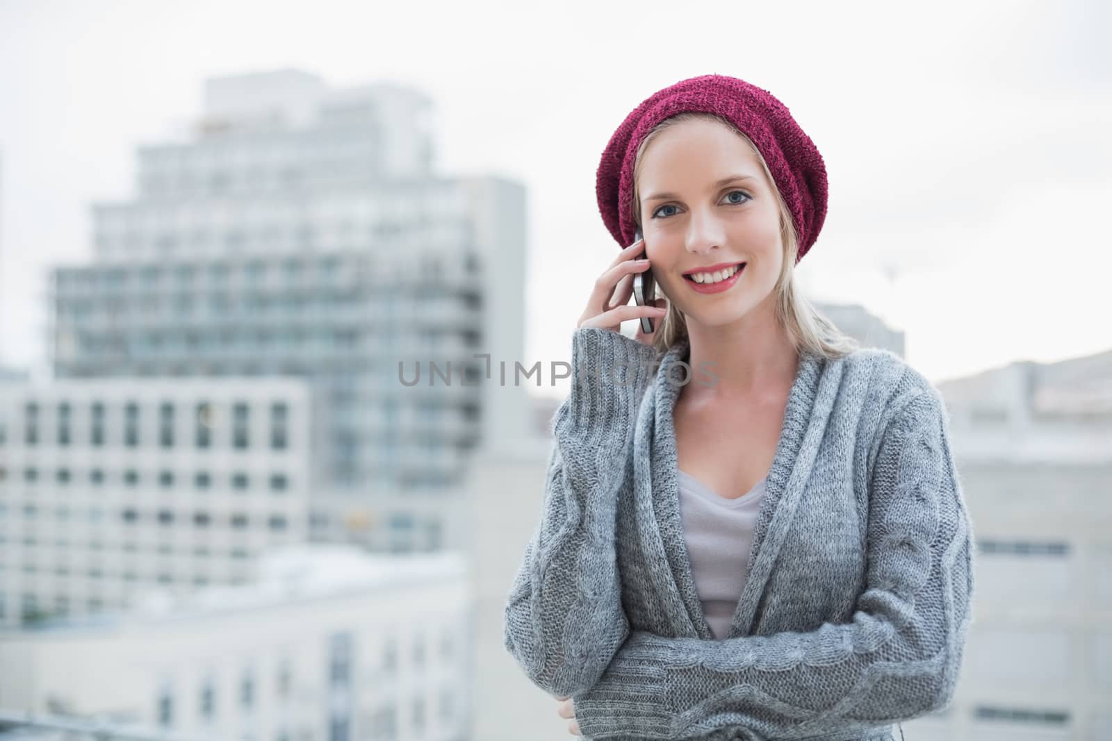 Smiling pretty blonde on the phone outdoors on urban background
