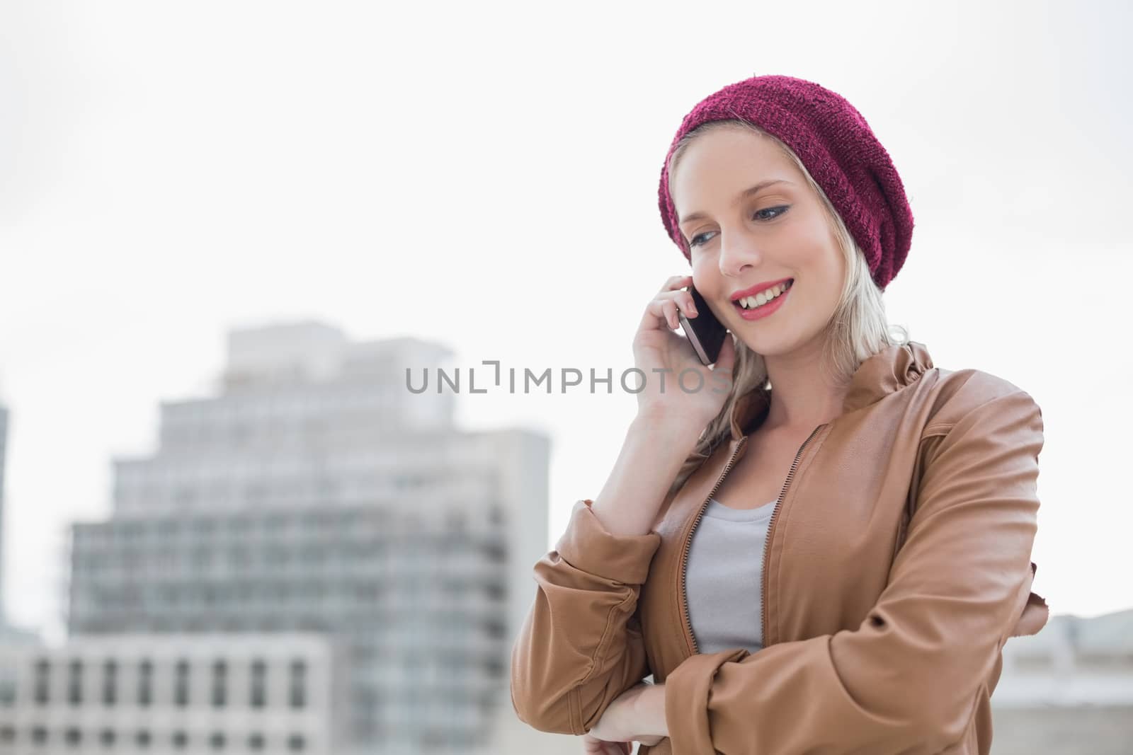 Smiling casual blonde on the phone outdoors on urban background