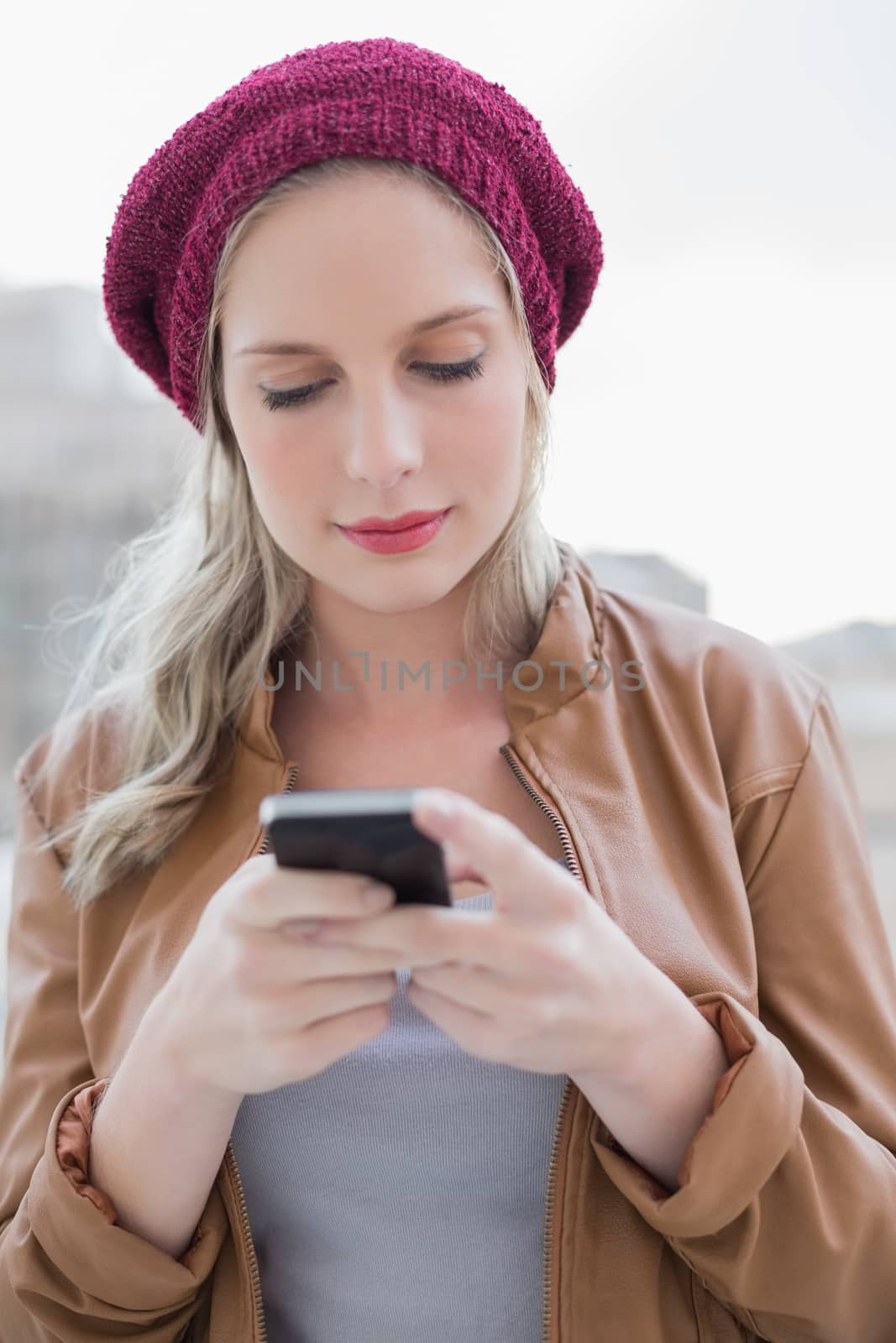 Peaceful casual blonde text messaging outdoors by Wavebreakmedia