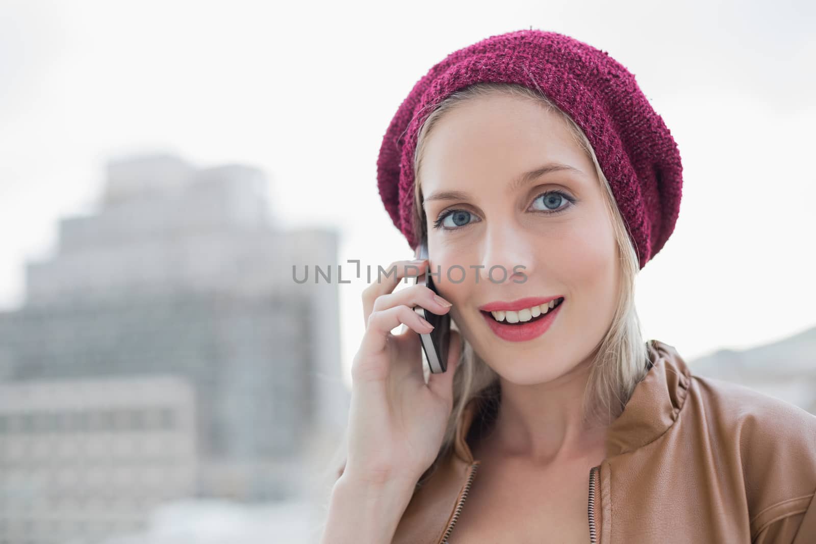 Surprised casual blonde on the phone outdoors on urban background