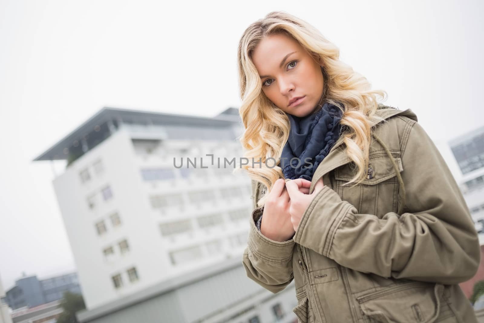 Serious attractive blonde posing outdoors on urban background