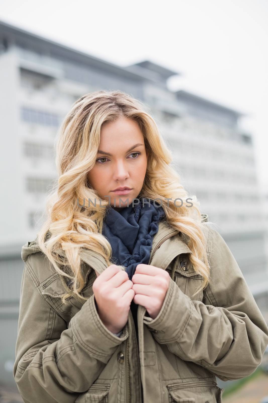 Worried trendy blonde posing outdoors on urban background