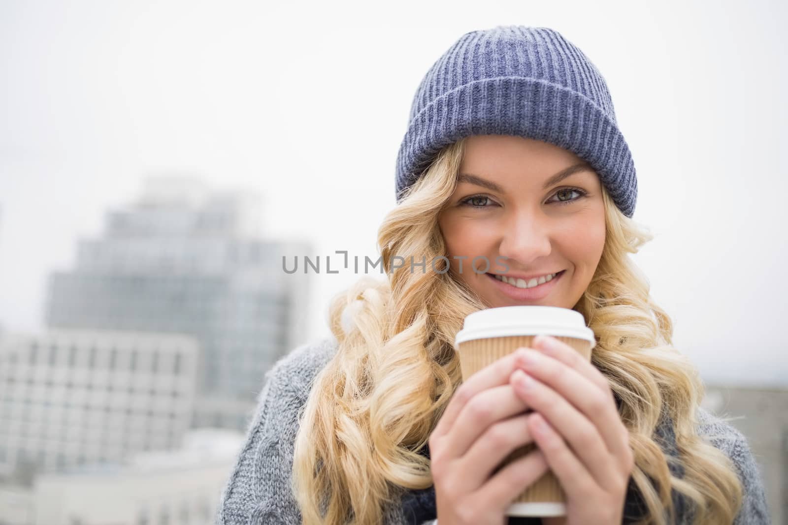 Cheerful pretty blonde having coffee outdoors on urban background