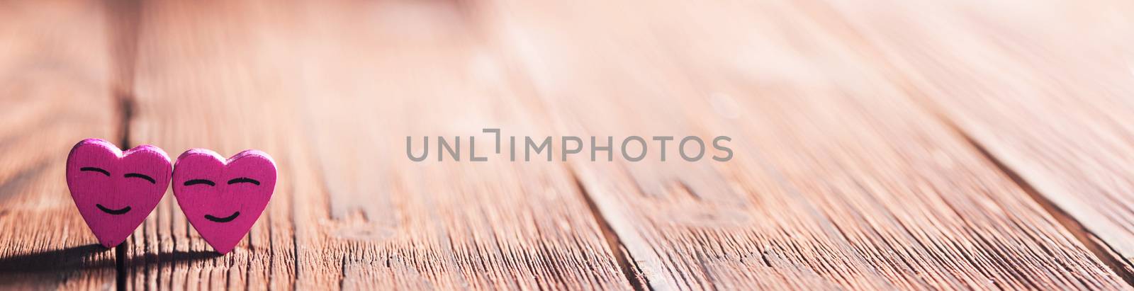 Two pink smiling hearts on wooden background with copy space for text