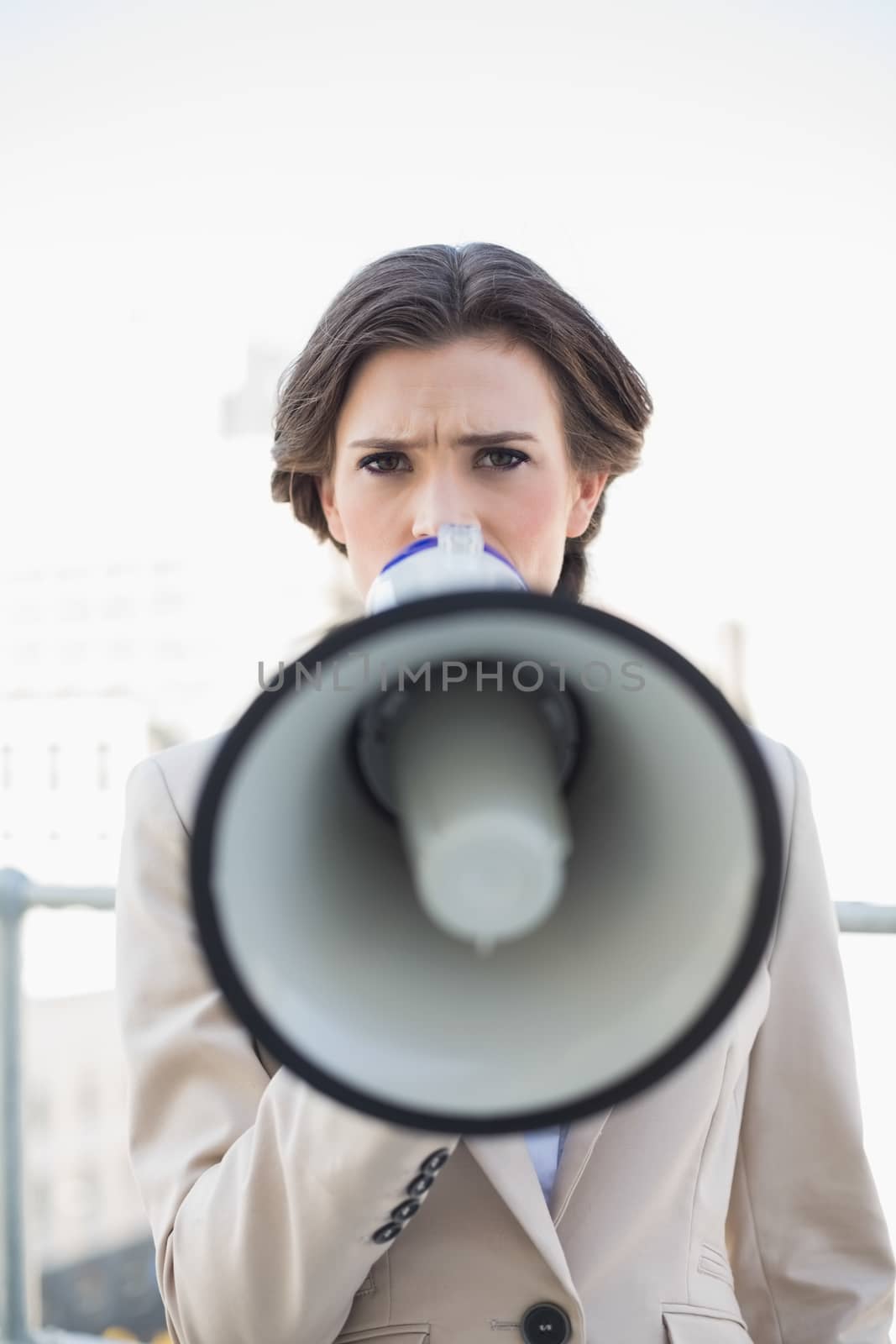 Frowning stylish brown haired businesswoman speaking in a megaphone by Wavebreakmedia