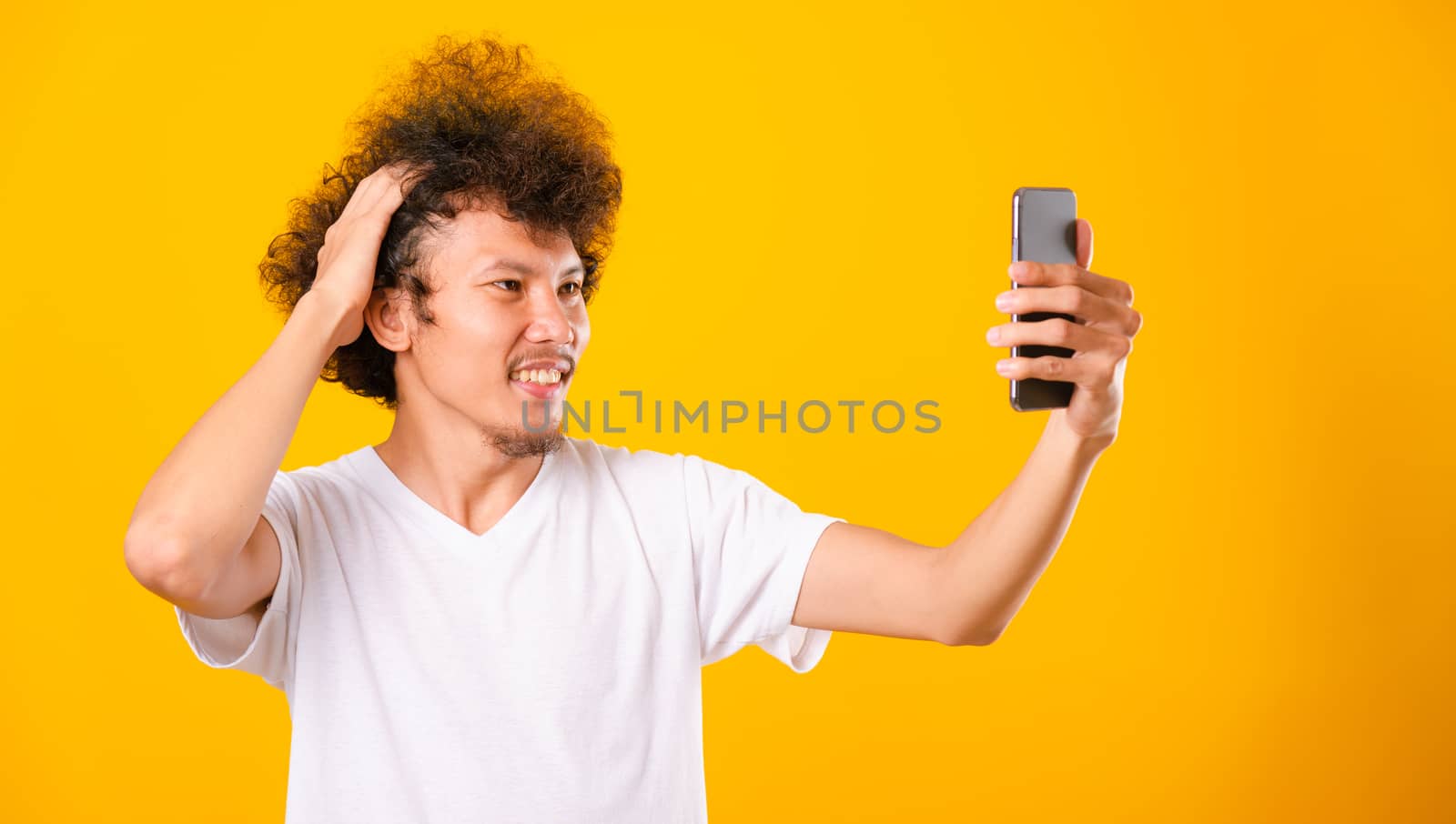 Portrait asian handsome man curly hair taking selfie with mobile by Sorapop