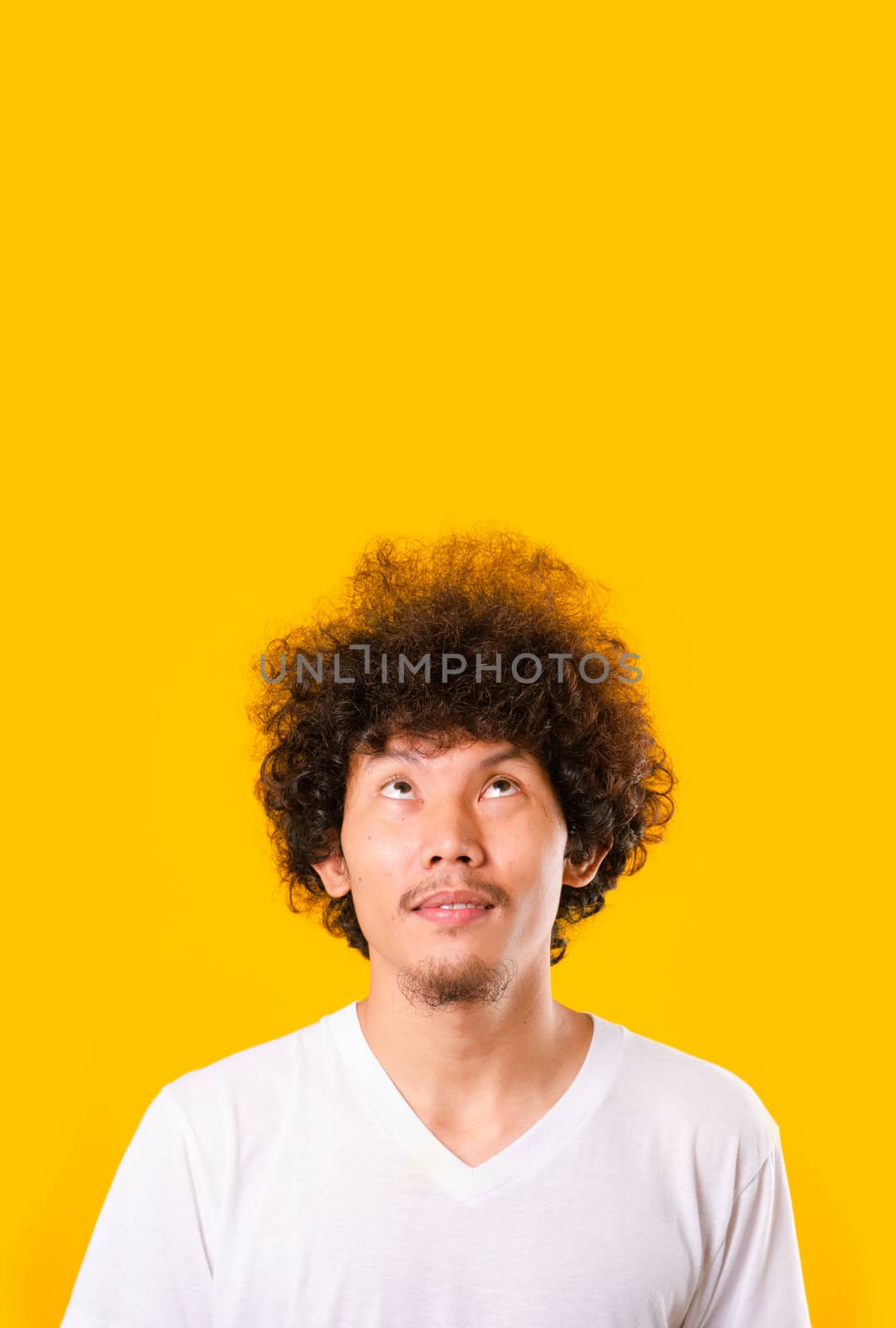 Asian handsome man with curly hair looking up see he hair isolate on yellow background with copy space for text