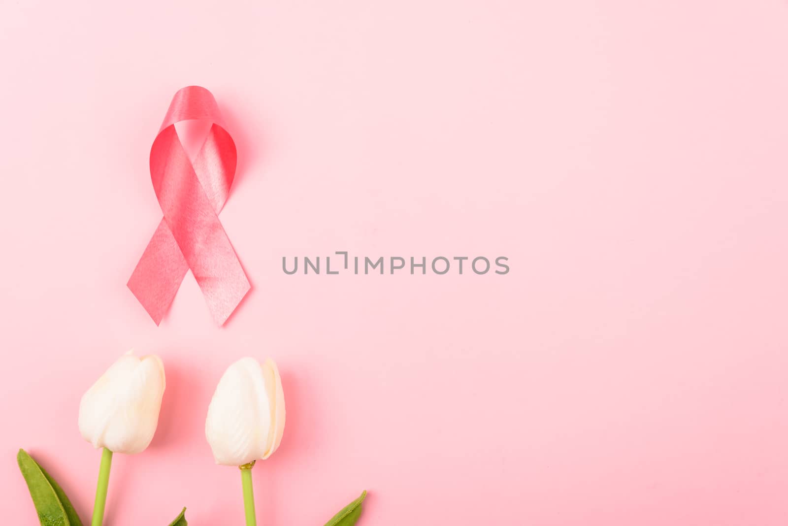 Breast cancer month concept, flat lay top view, pink ribbon and Tulip Flower on pink background with copy space for your text