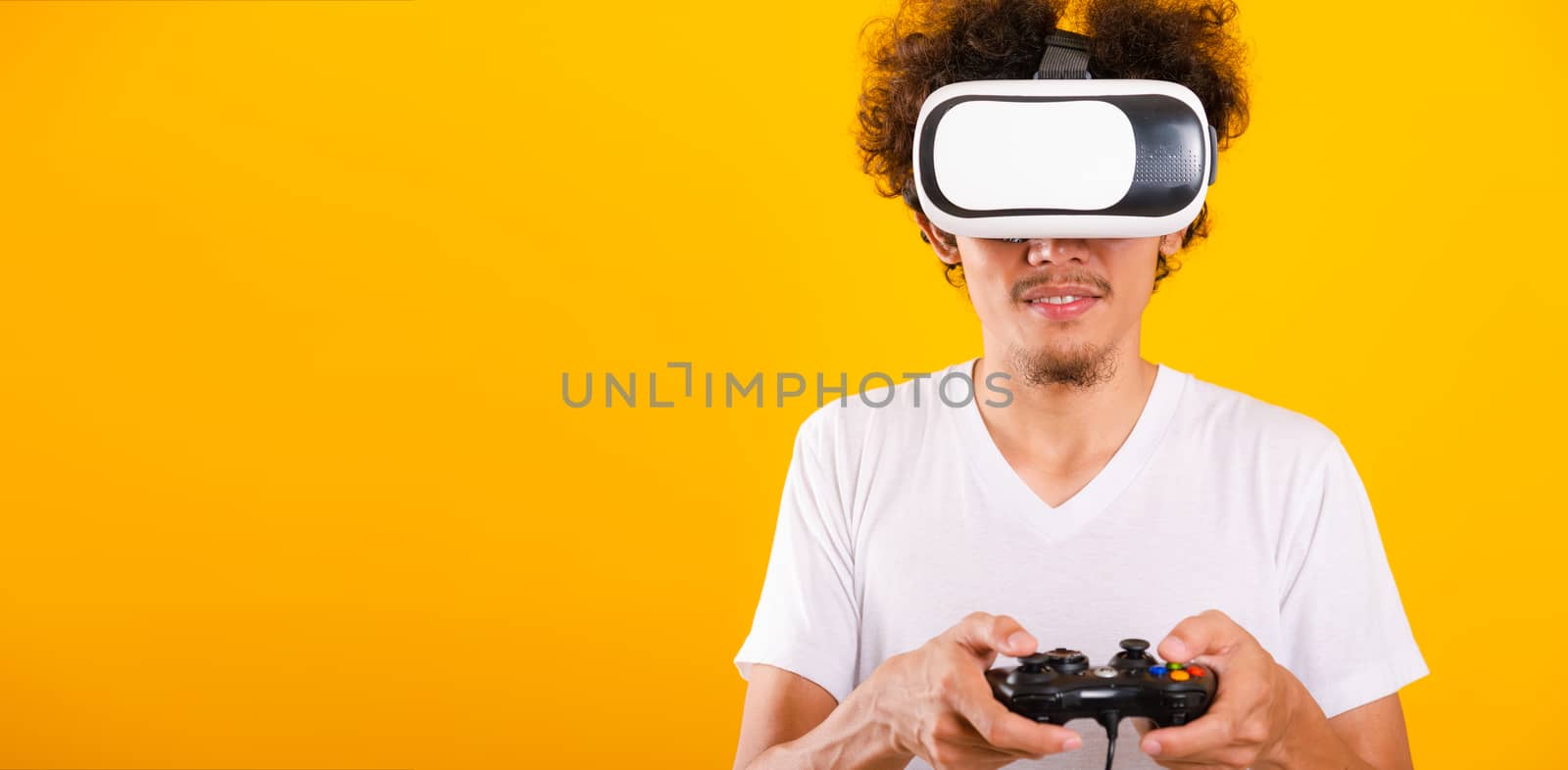 Asian handsome man with curly hair play game he using virtual re by Sorapop