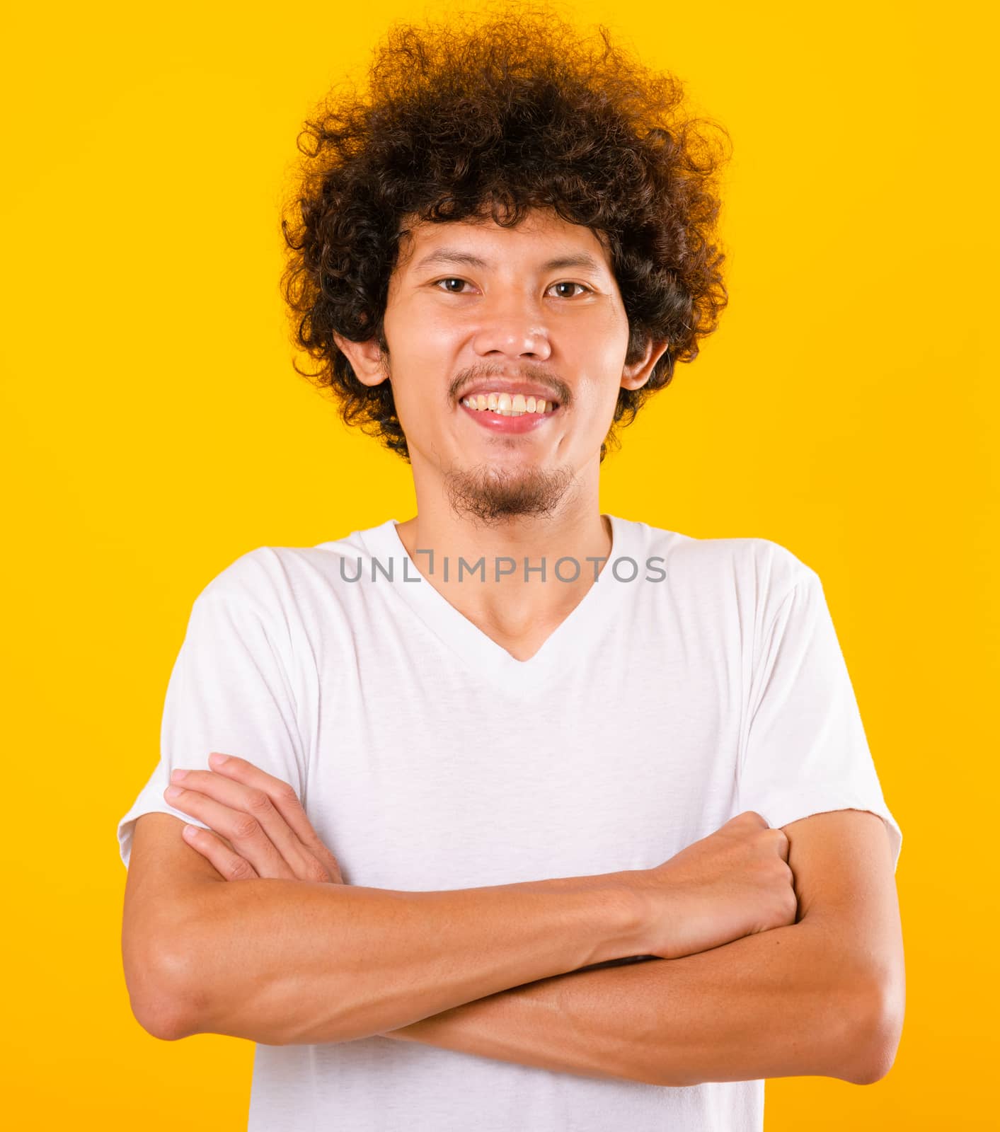 Portrait of Asian handsome man with curly hair with arms crossed isolate on yellow background