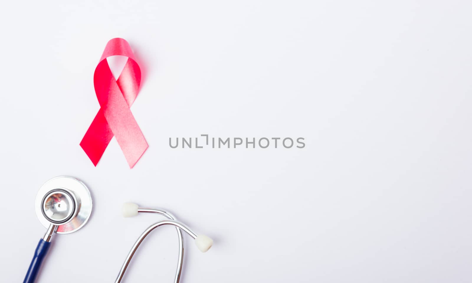 Breast cancer month concept, flat lay top view, pink ribbon and stethoscope on white background with copy space for your text