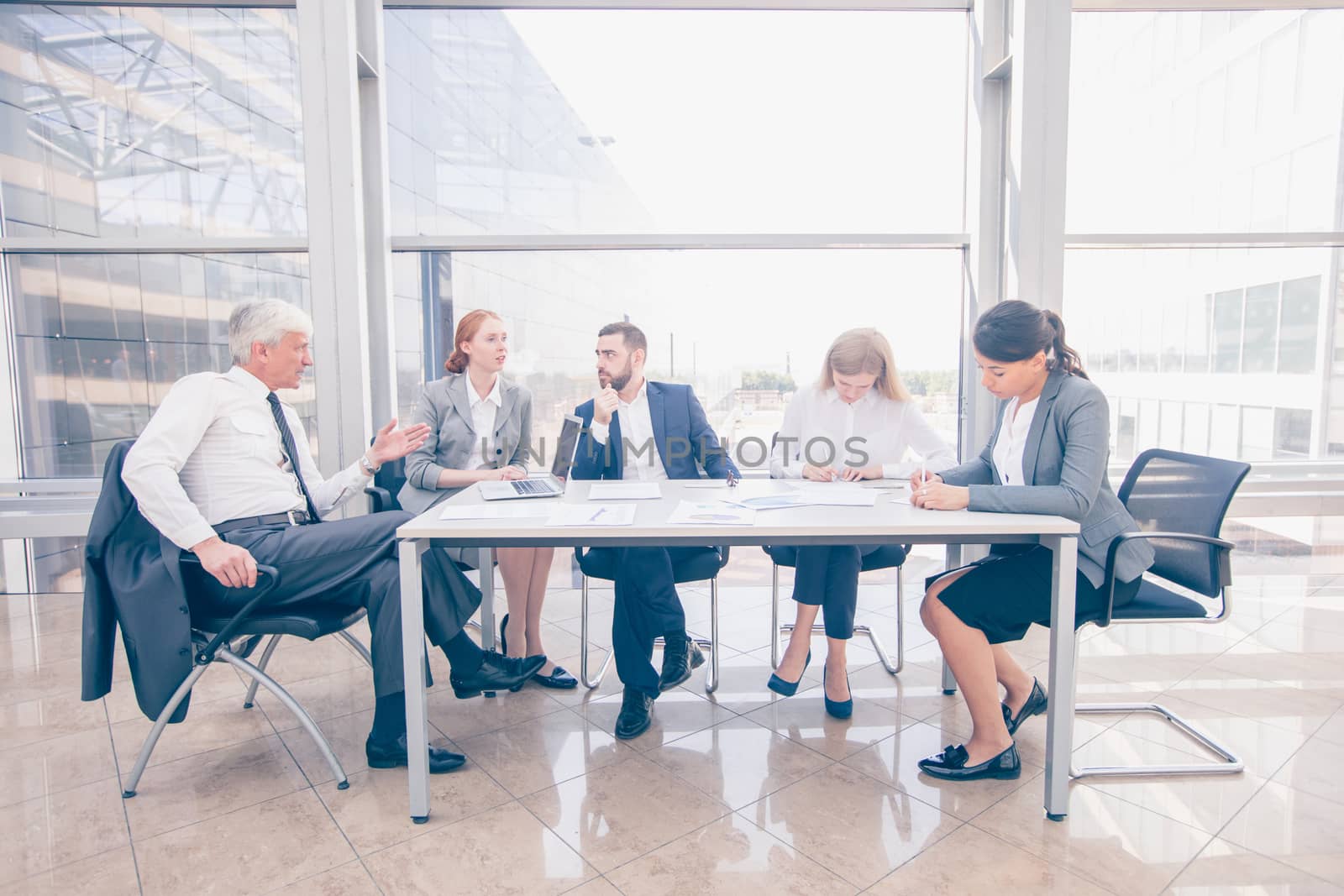 Business team sitting by the table and working with laptop and documents in office