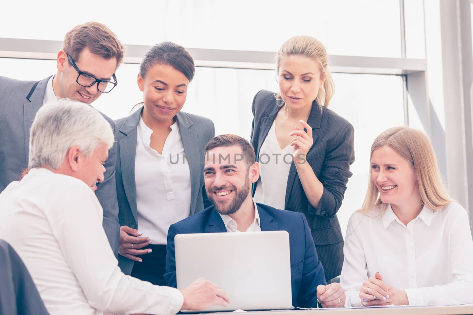 Business team sitting by the table and working smiling with laptop and documents in office