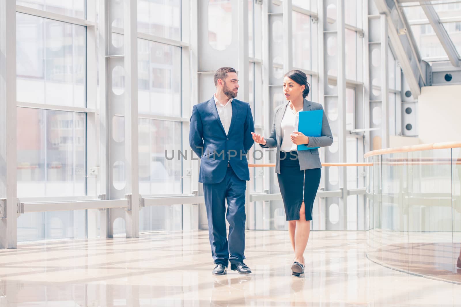 Businessman and businesswoman walk together and talk about business holding coffee in hand