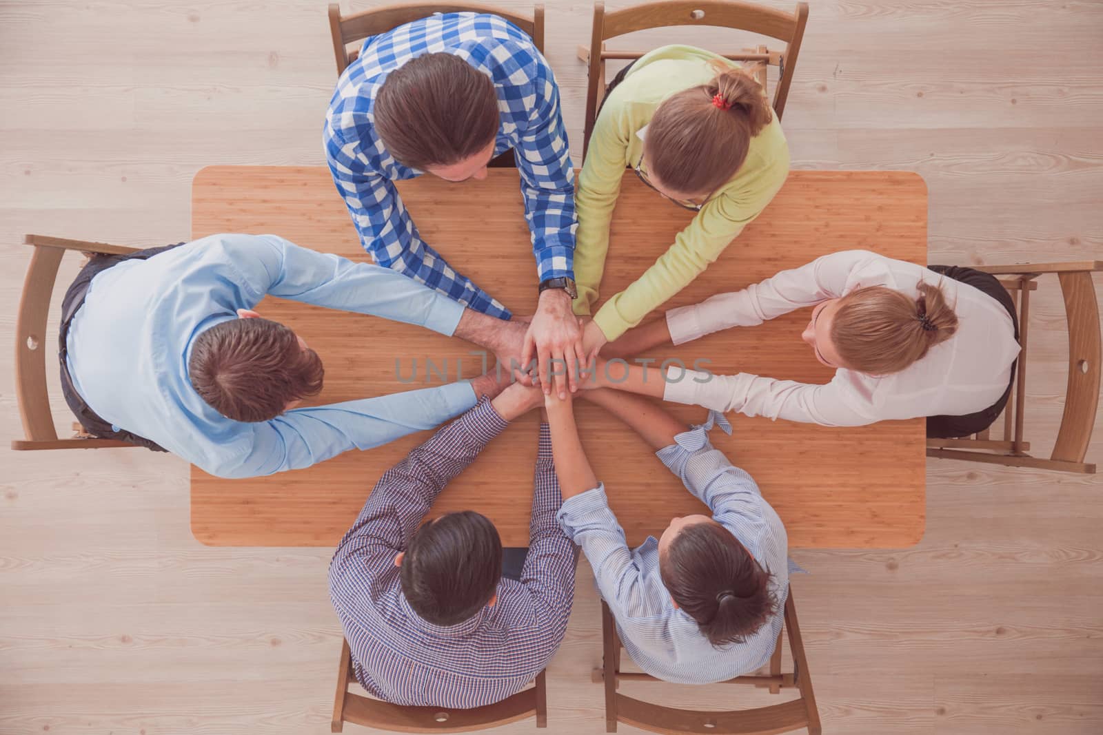 Top view of business people putting their hands on top of each other stacking at conference