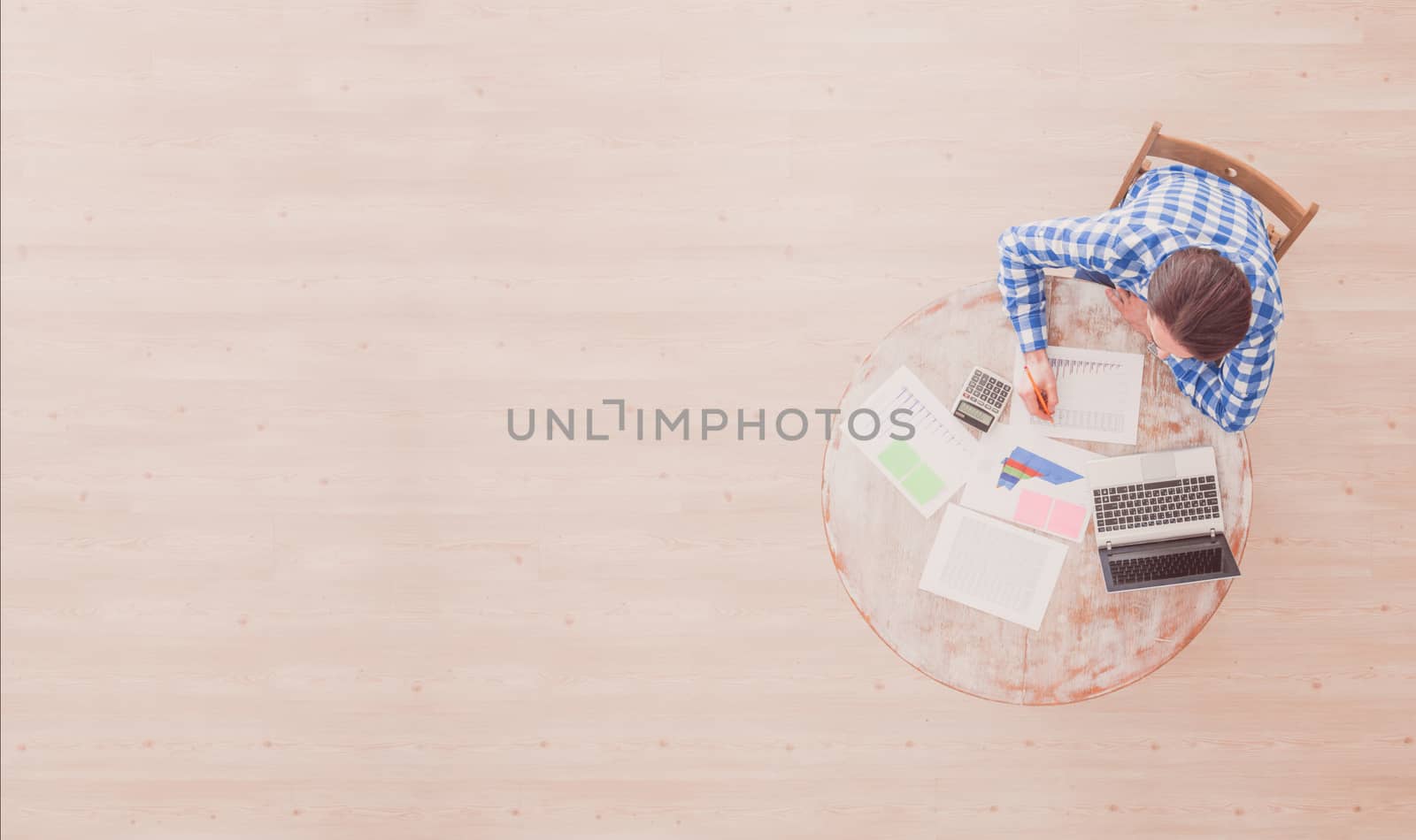 Businessman working with finance documents at office with laptop, and graph data papers on his desk, top view with copy space