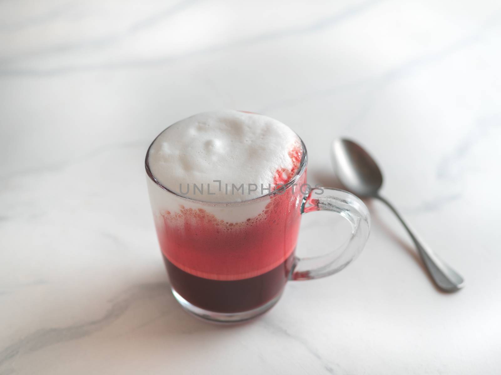 Trendy drink: pink red velvet latte. Beetroot cappuccino or latte in glass cup on white marble background. Copy space for text.
