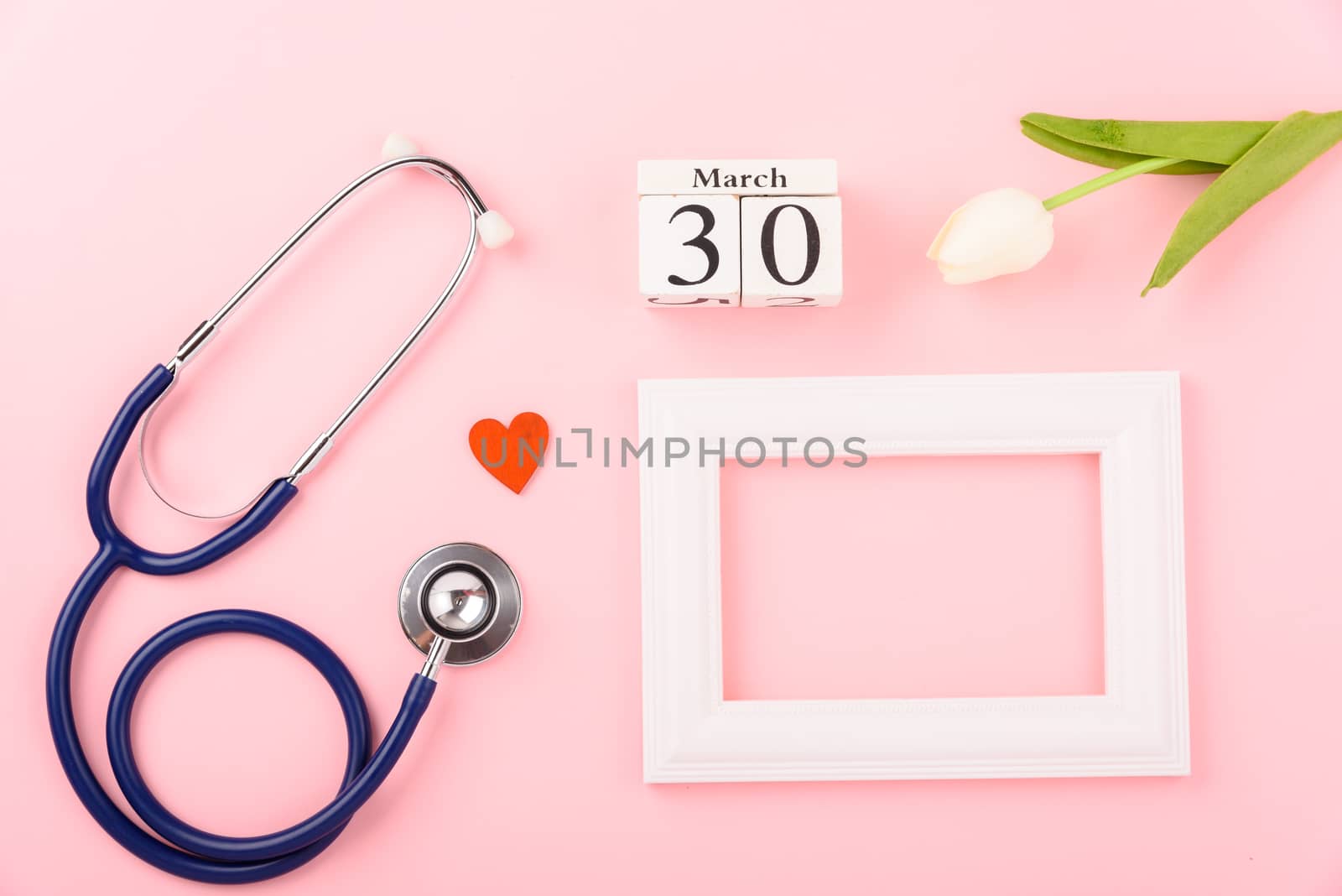 Doctor's Day concept, flat lay top view, equipment medical red heart stethoscope and photo frame on pink background, care patient in hospital with copy space for text