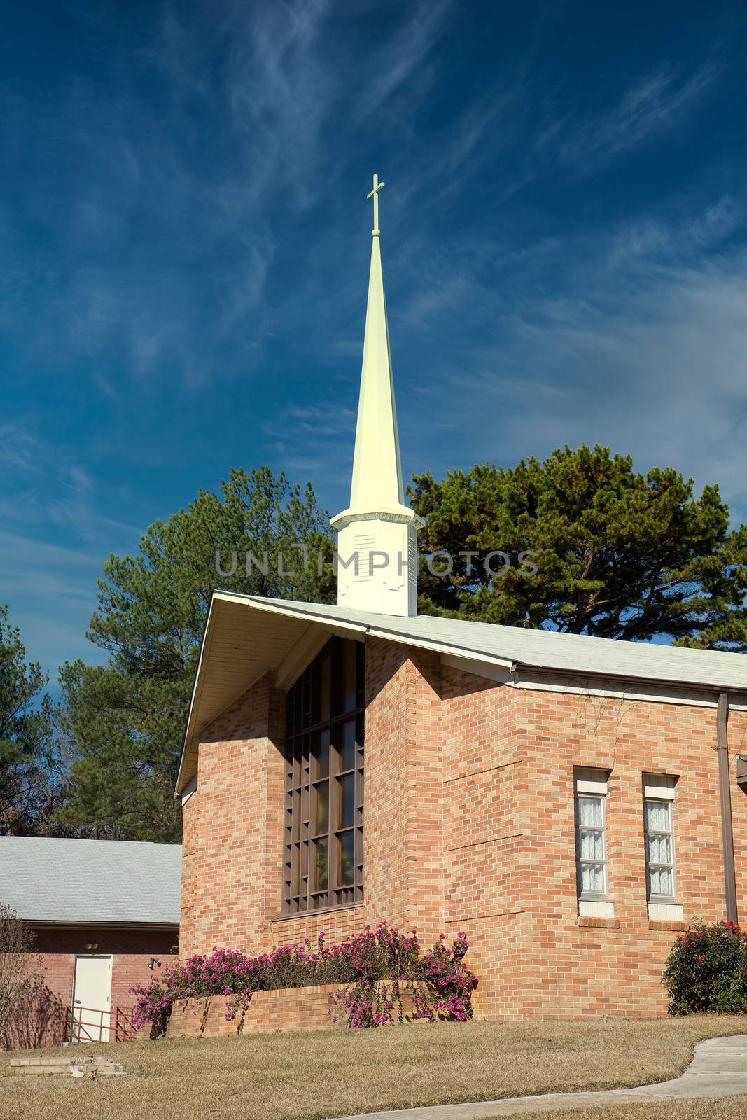 A small brick church and steeple against a blue sky
