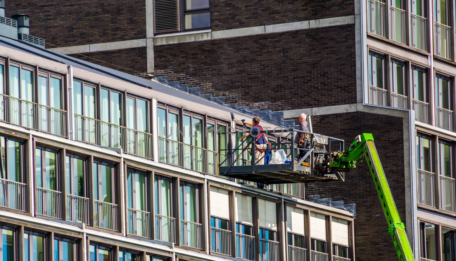 workers on a elevator platform, repairs on a apartment complex in the city of Amsterdam, The Netherlands by charlottebleijenberg