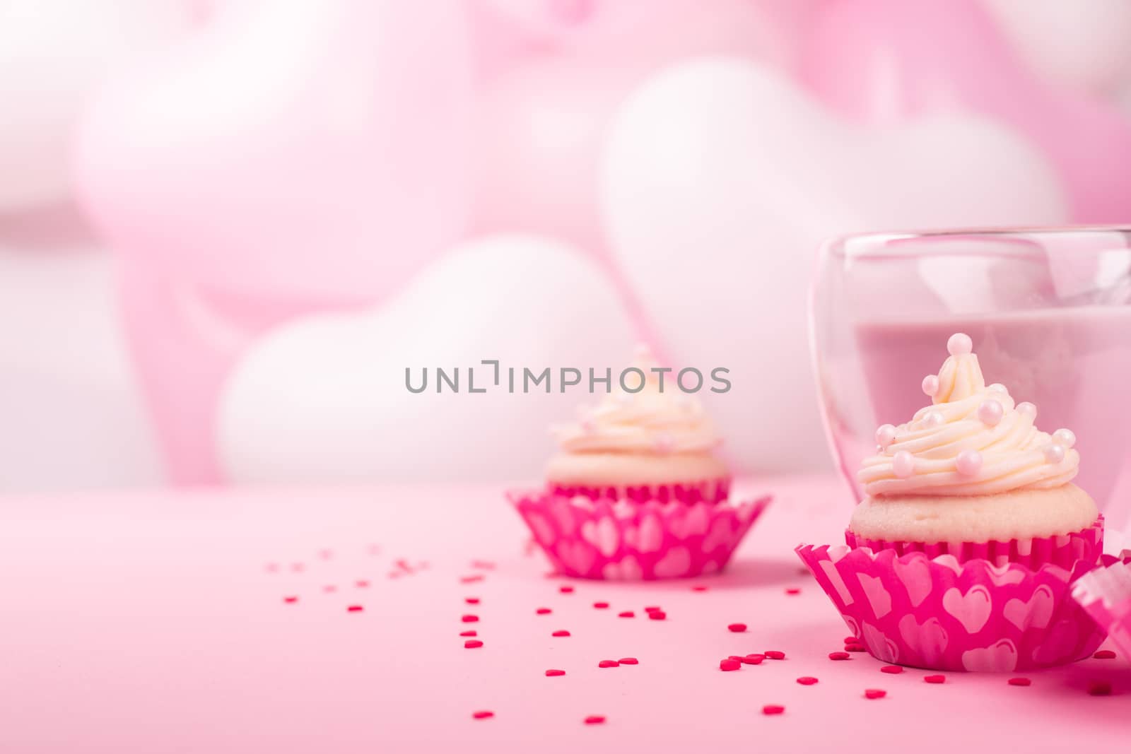 Valentine day love cupcake decorated with cream and hot chocolate on pink heart balloons background with copy space for text