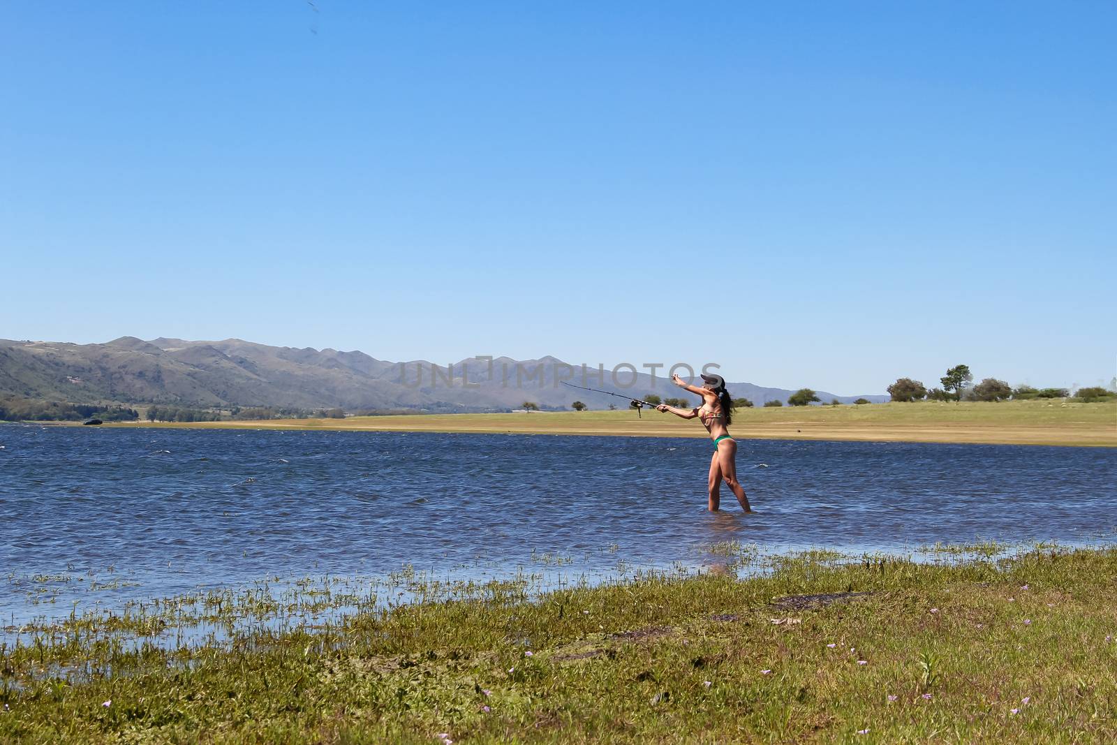beautiful young woman fishing the mountain lake by GabrielaBertolini