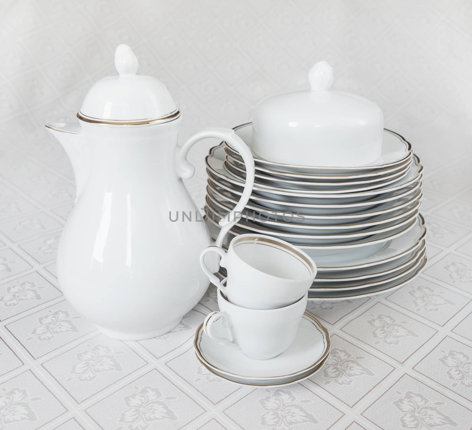 White crockery for tea: teapot, cup, serving plate and sugar bowl on a beautiful tablecloths