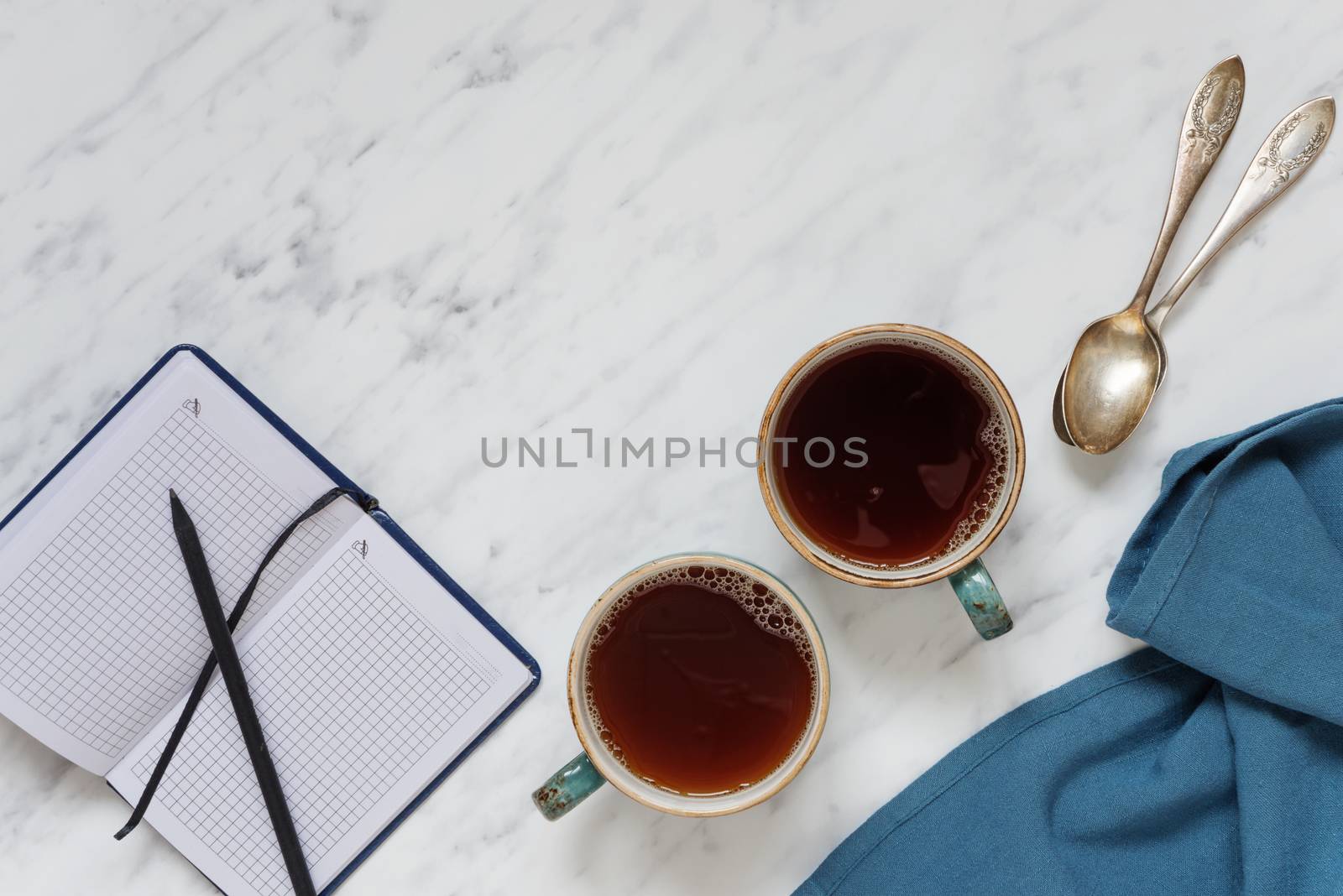 Morning composition with two cups of black coffee and a notebook on a marble surface, with space for text, top view