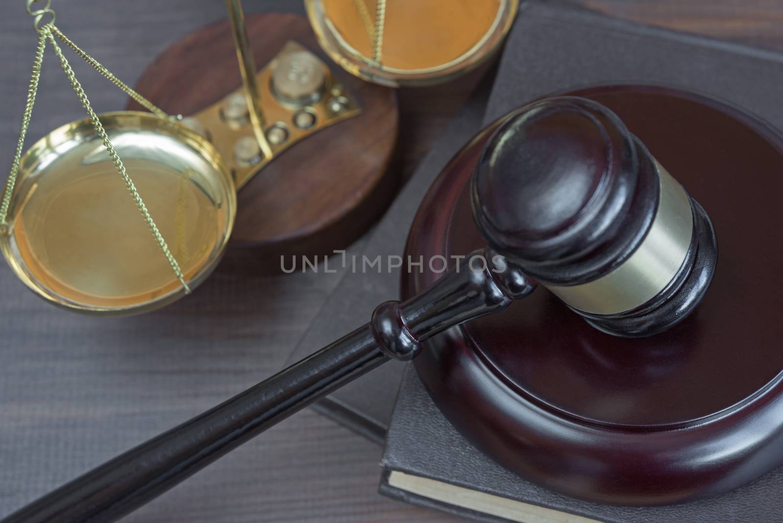 Wood gavel, soundblock, scales and stack of old books bound in leather on the wooden background