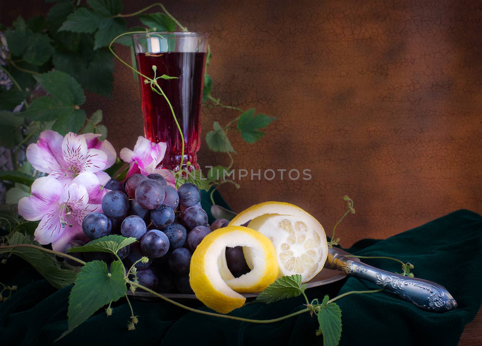 Still life in antique style with glass of wine, pink flowers, grapes and lemon on pewter plate, with copy-space