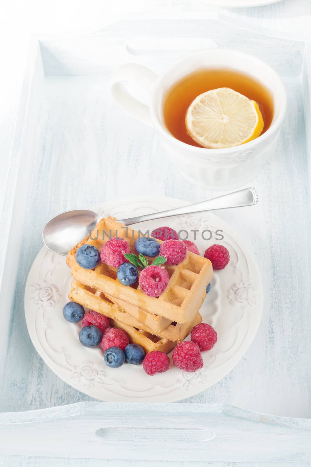 Continental breakfast with sweet waffles, berries and tea with lemon