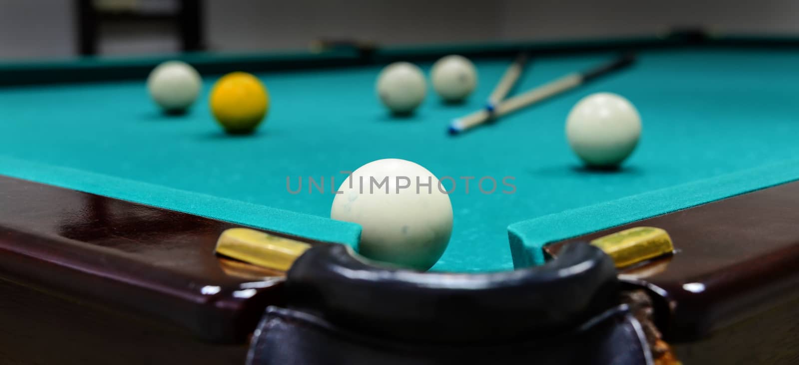 Billiard balls and two cue sticks on green game table