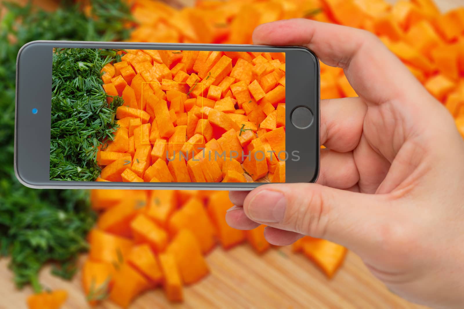Fresh vegetables before loading into pan. Ingredients for cooking. Carrots on smartphone screen.