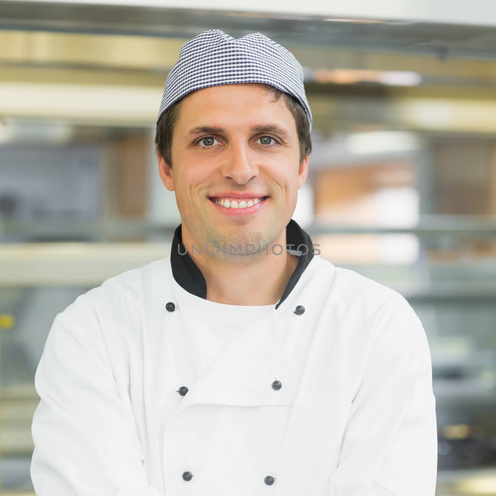 Handsome young chef smiling at camera posing in a kitchen