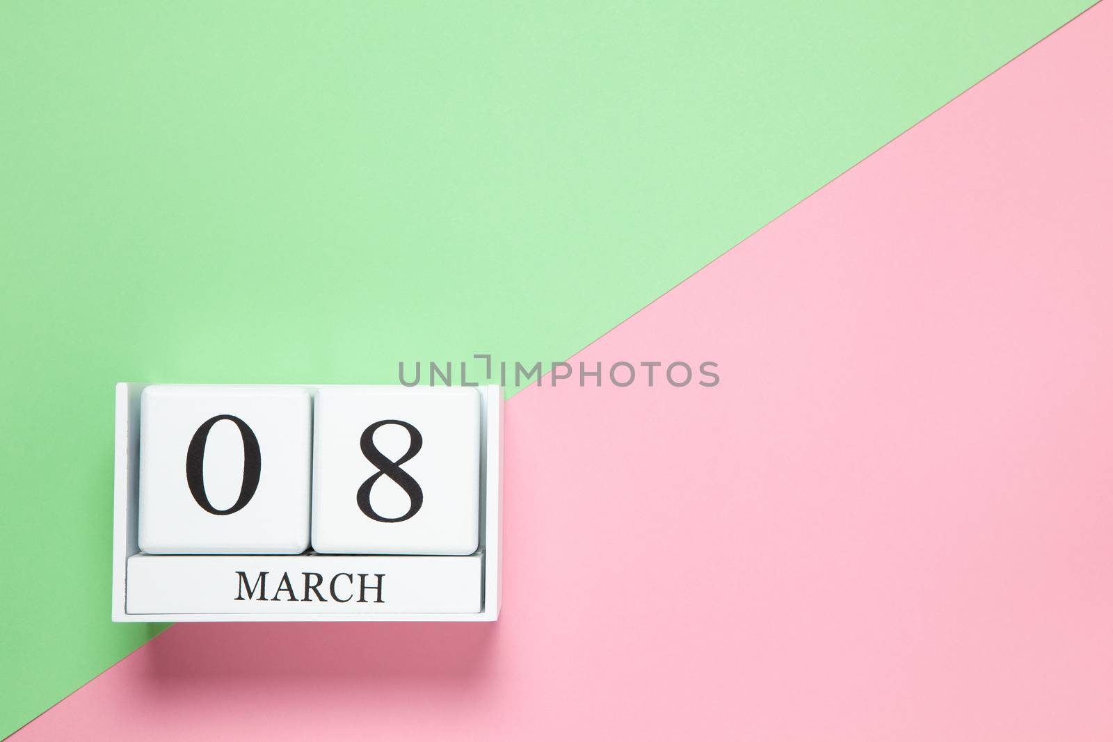 Perpetual calendar with date of March 8 on two-color background pink and green. Flat lay. Top view. International Happy Women's Day celebration concept. Horizontal, close-up, copy spase. For delivery.