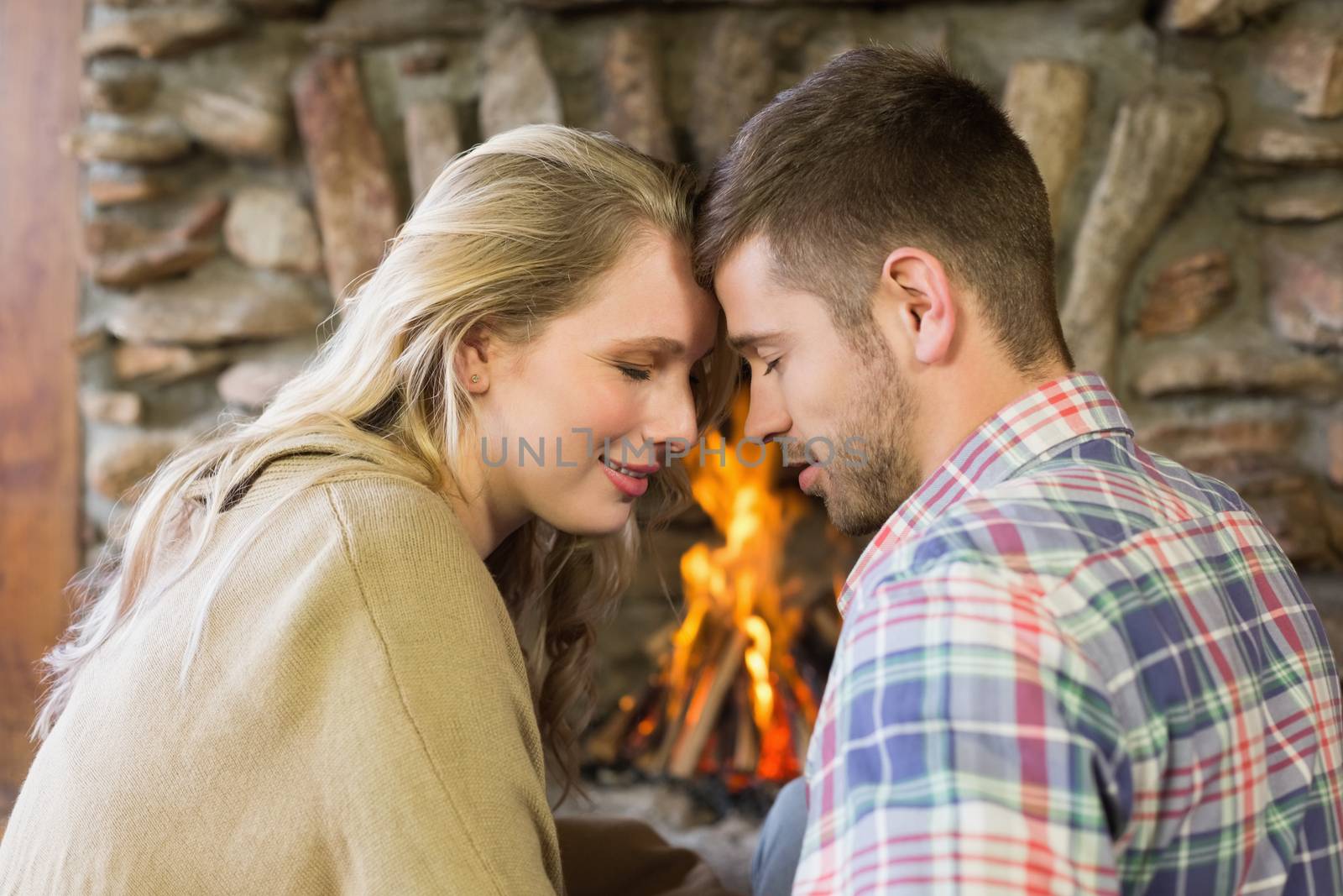 Romantic couple with eyes closed in front of fireplace by Wavebreakmedia