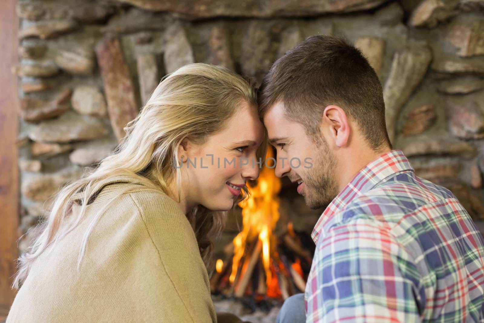 Side view of a romantic young couple in front of lit fireplace