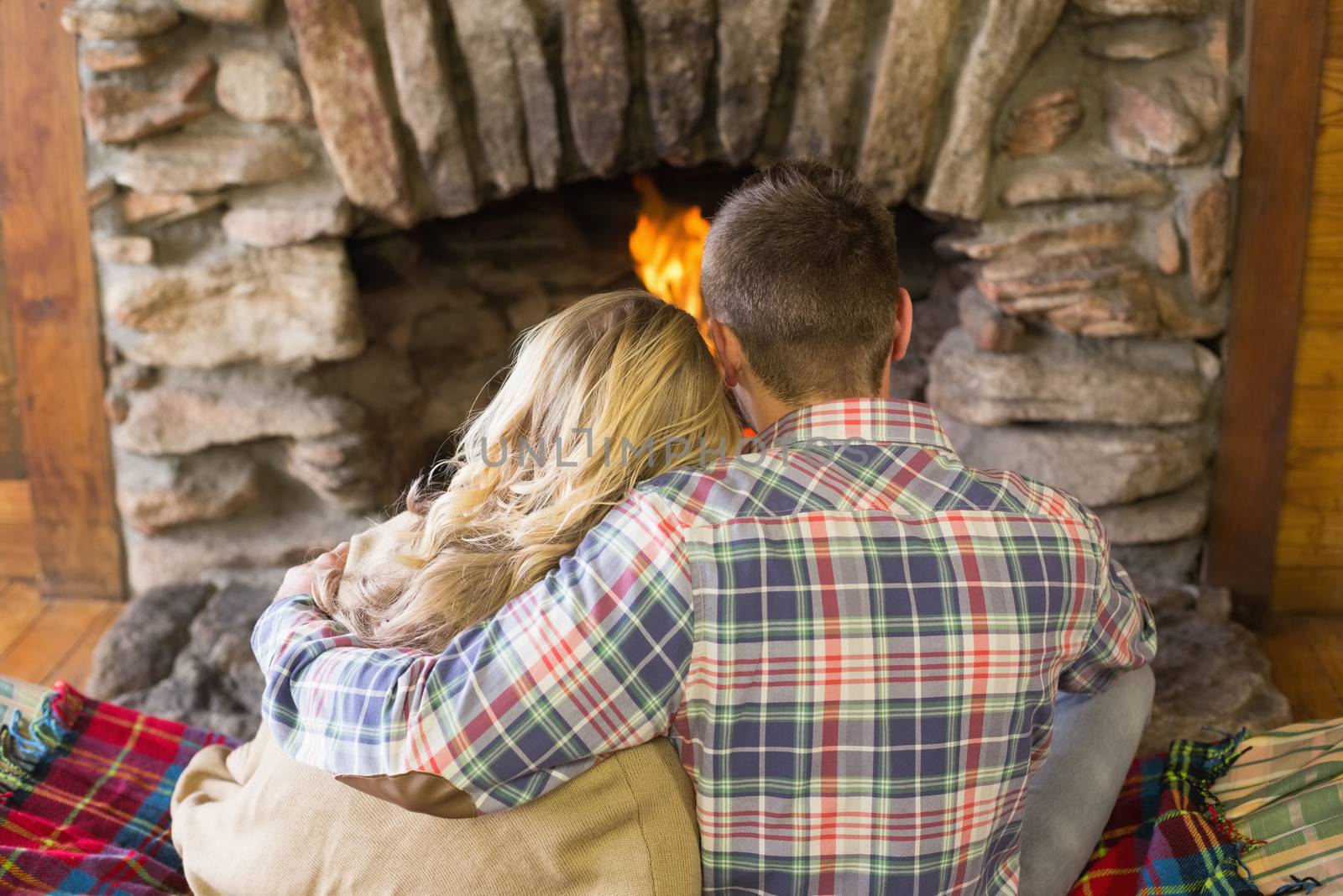 Romantic couple sitting in front of lit fireplace by Wavebreakmedia