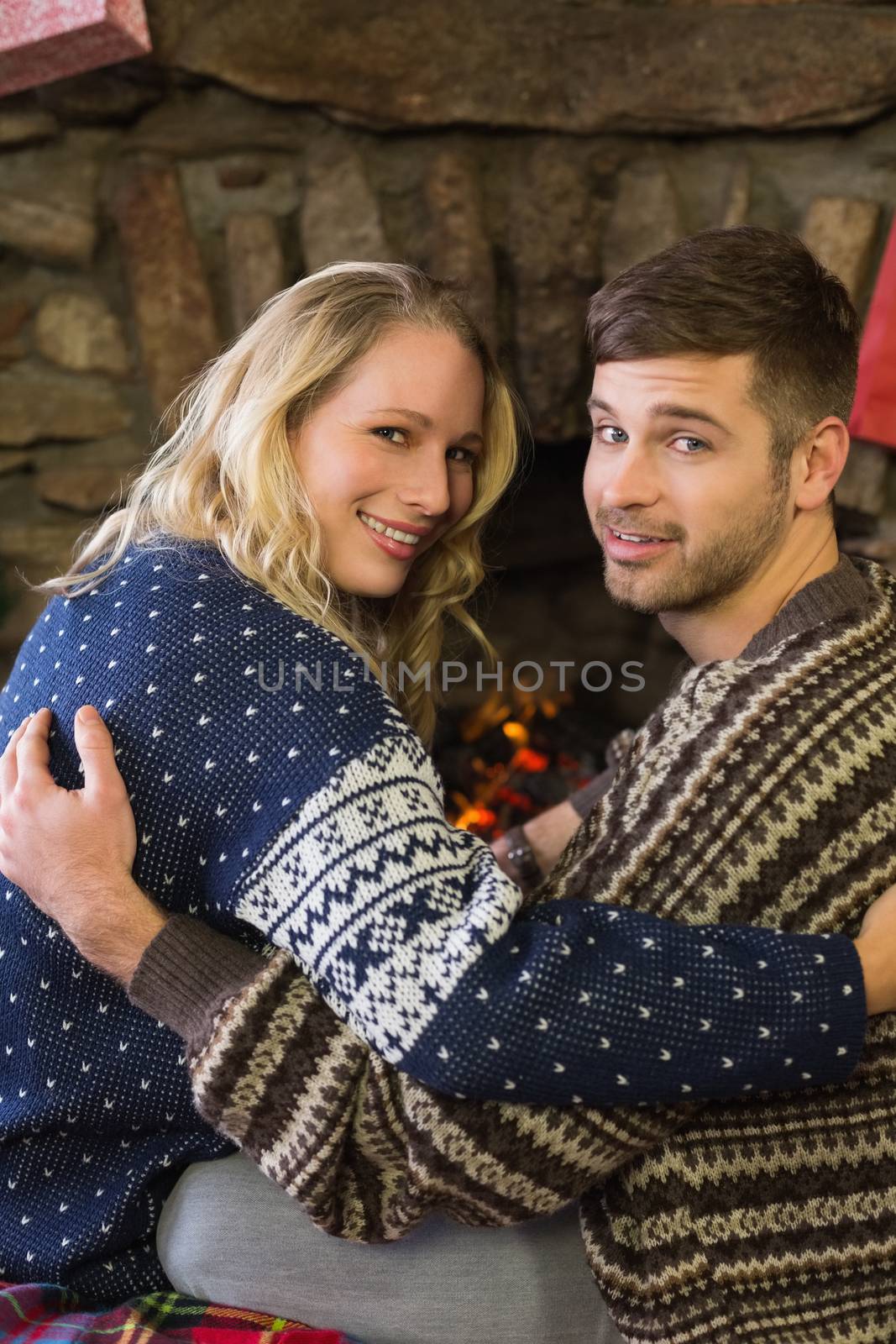 Rear view portrait of a romantic young couple smiling in front of fireplace